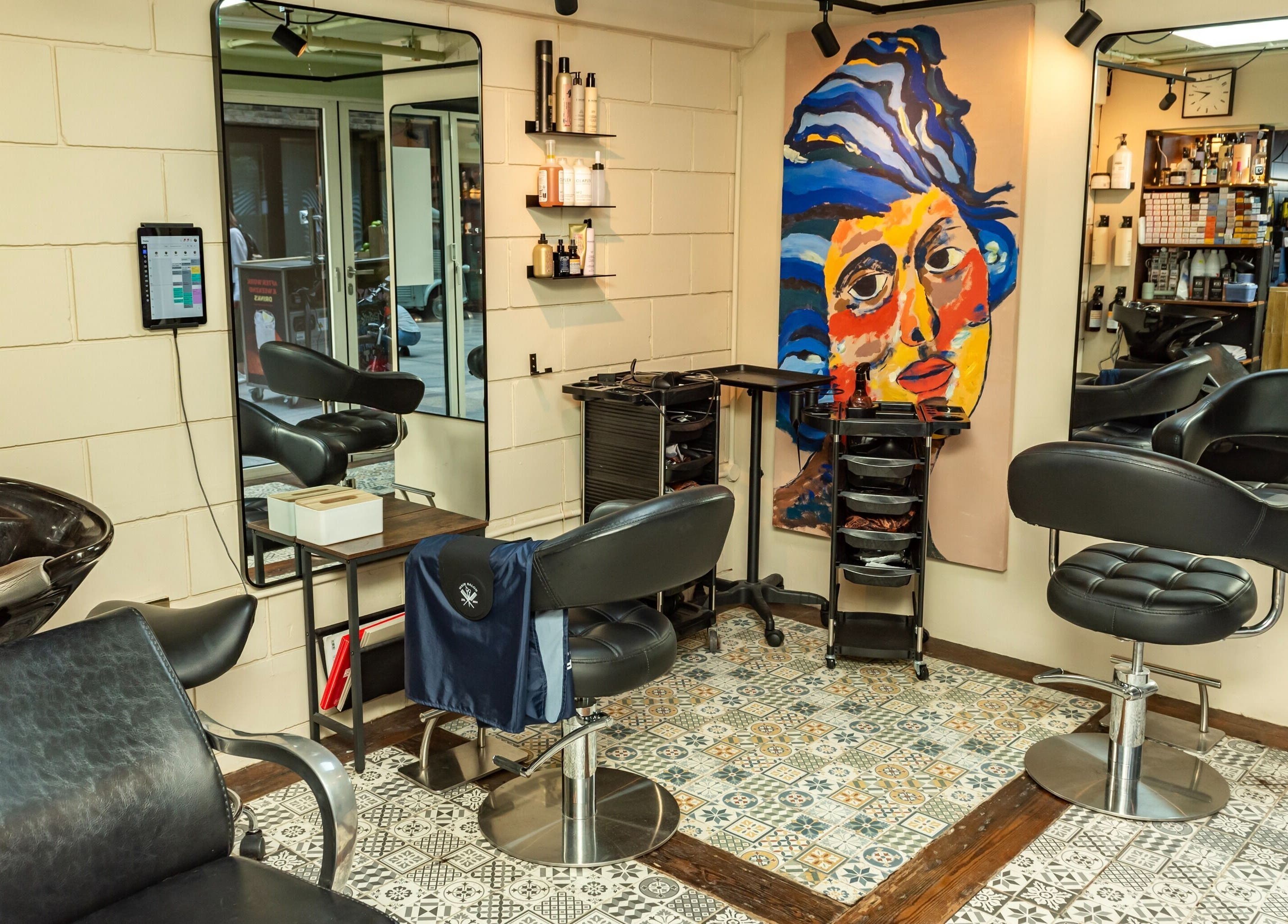 Modern salon at Hilario, London, England, GB featuring vibrant mural, stylish chairs, and quality amenities.