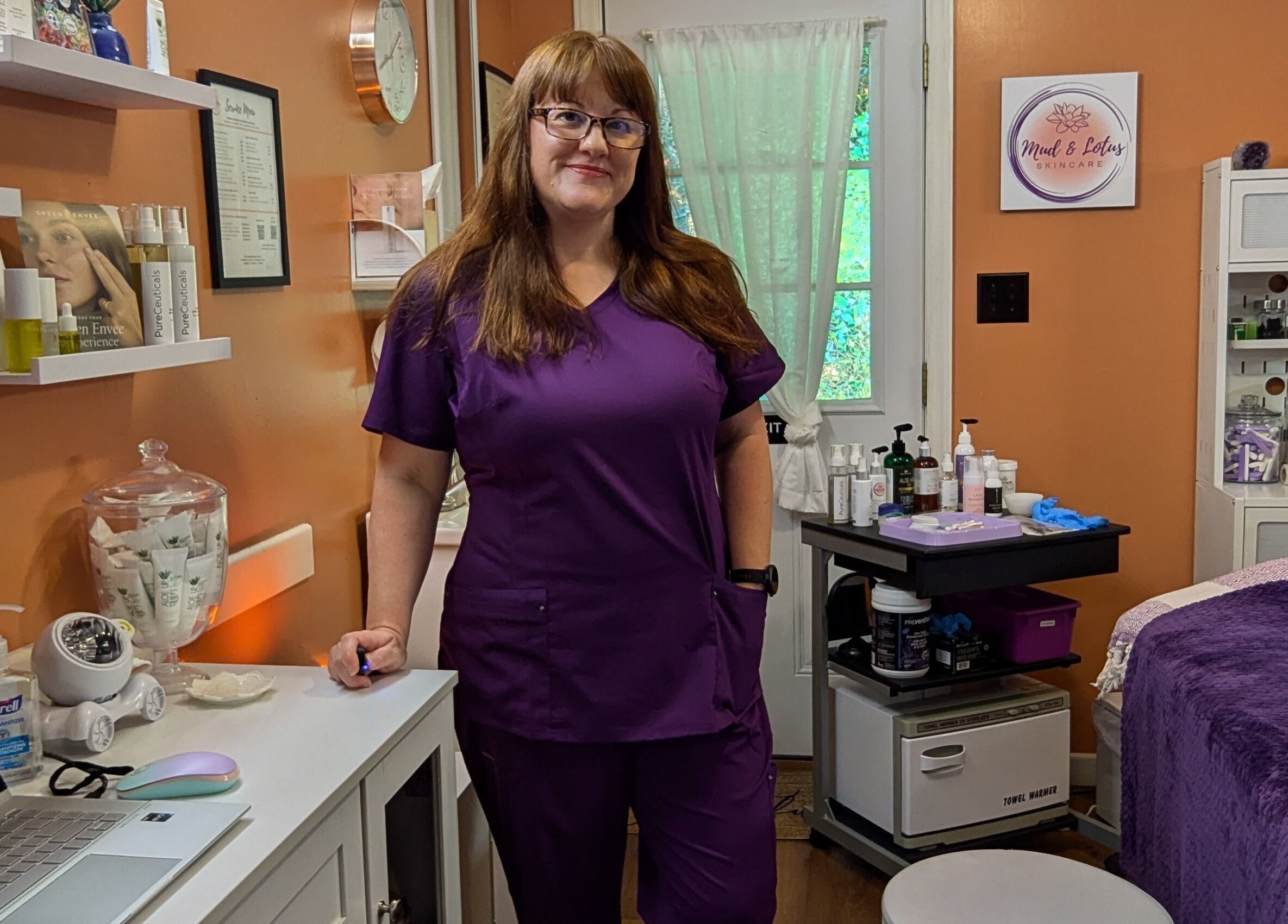 Professional at Mud and Lotus Skincare, Burnsville, North Carolina, with treatment products and serene interiors.