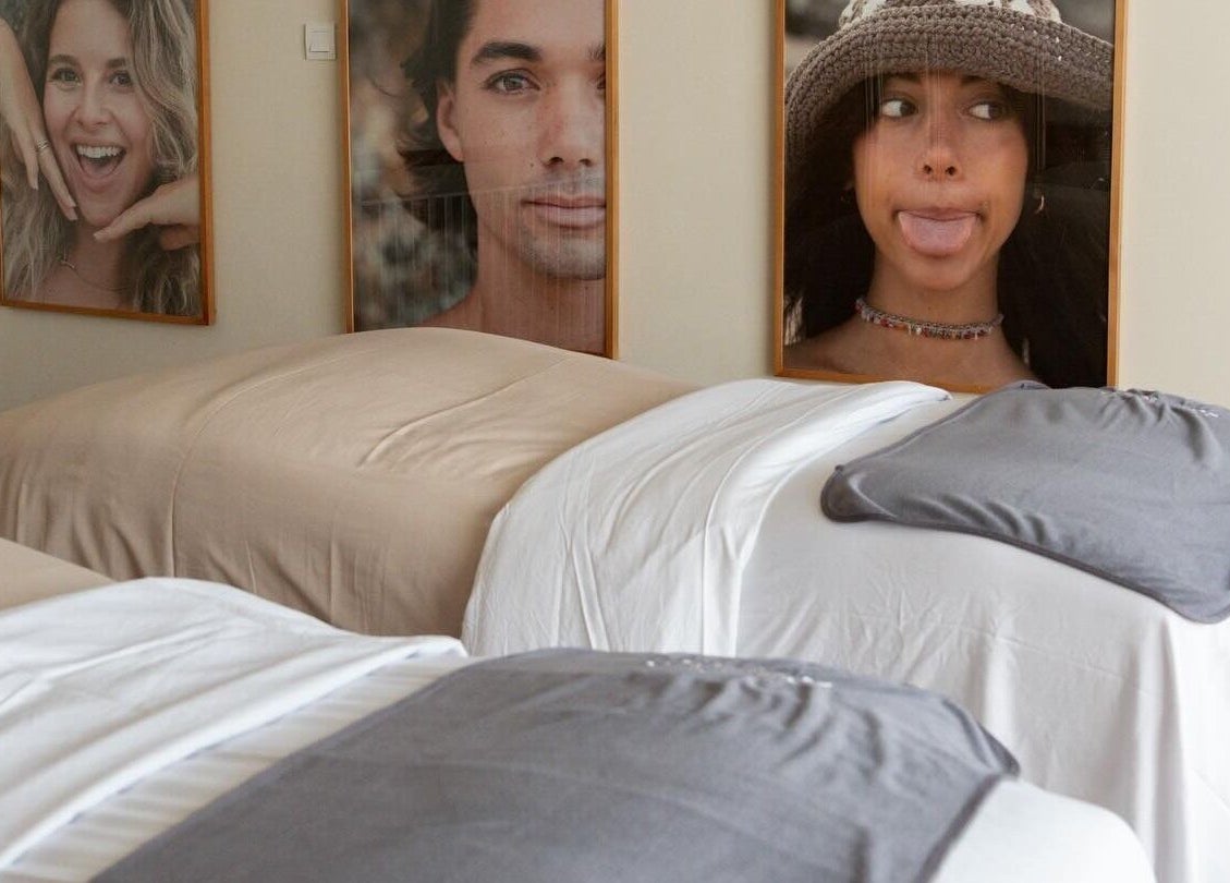 Cozy spa beds in Salty Face Bali, Uluwatu, adorned with smiling portraits.