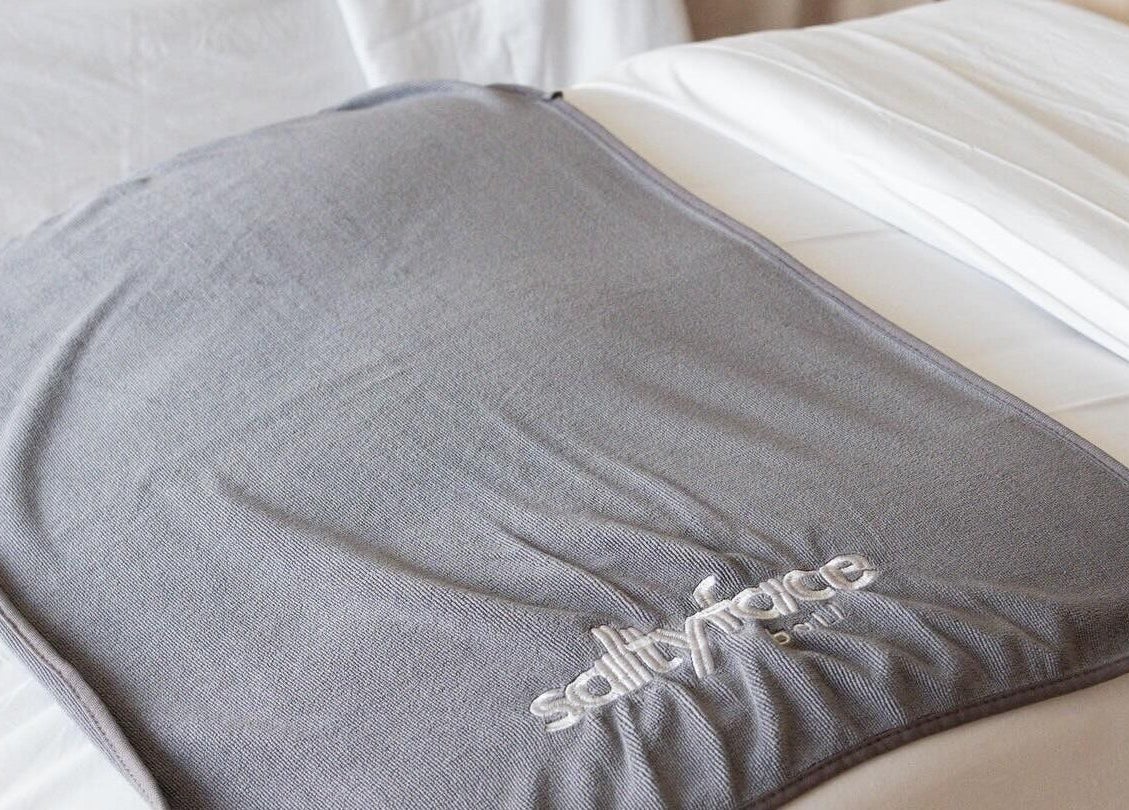 Plush gray blanket at Salty Face Bali in Uluwatu offers comfort and relaxation.