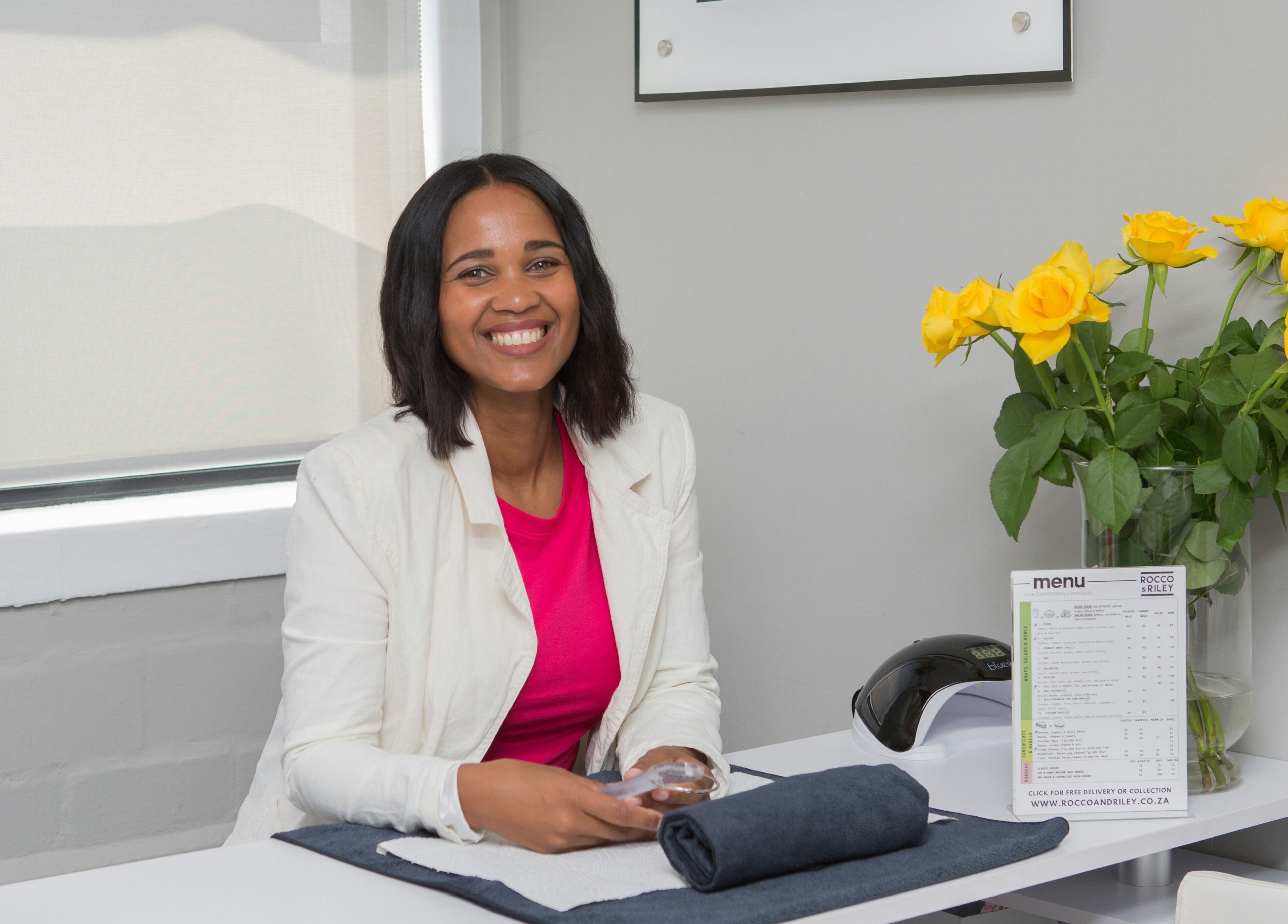 Welcoming smile at Chontell at Dames en Here, Stellenbosch, Western Cape, ZA, with yellow flowers on table.