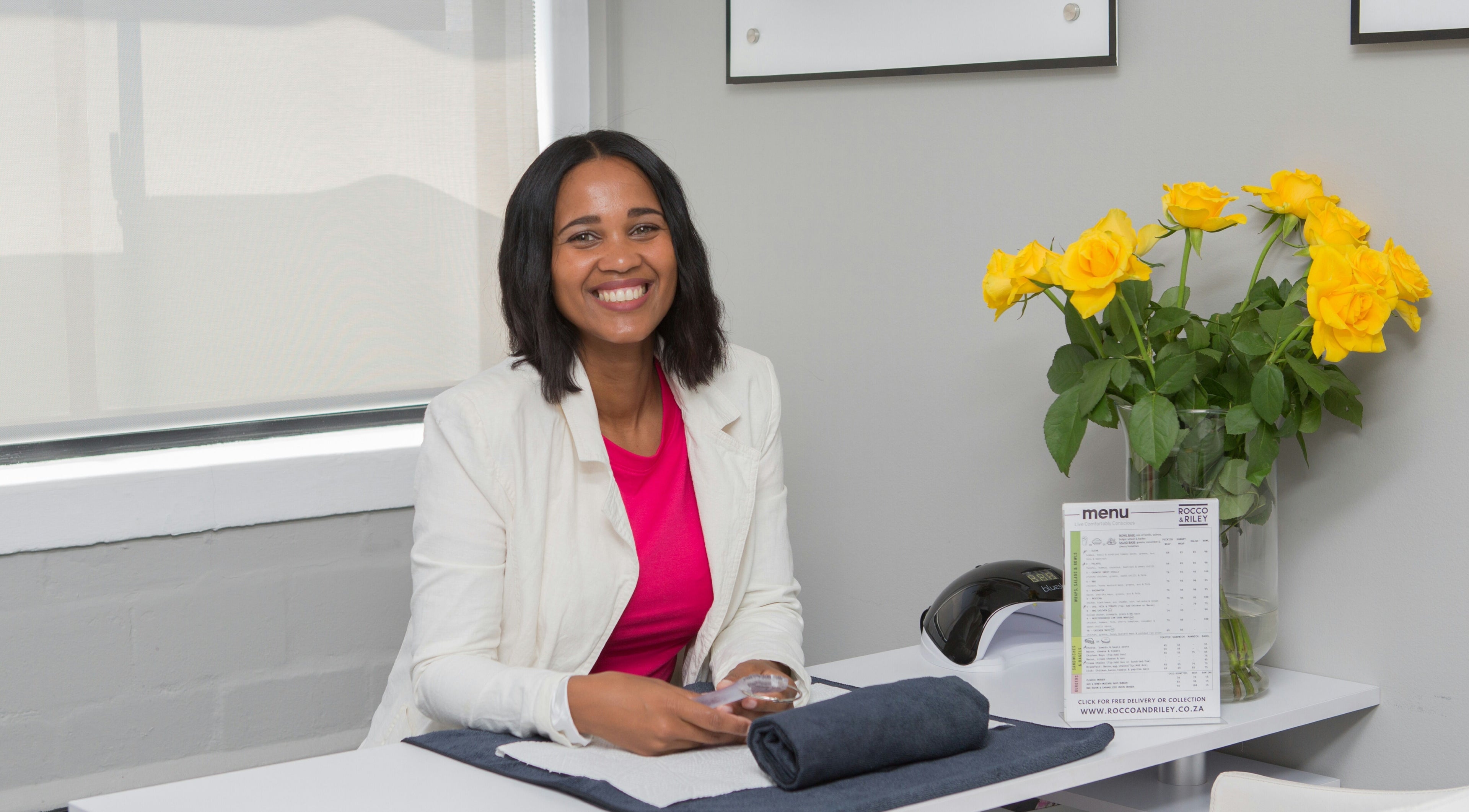 Welcoming smile at Chontell at Dames en Here, Stellenbosch, Western Cape, ZA, with yellow flowers on table.