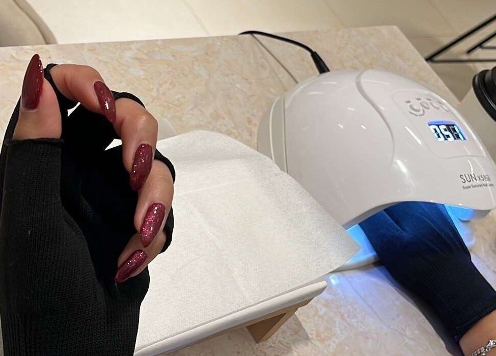 Elegant nail treatment at Nai Spa, Riyadh, Riyadh Province, SA, featuring a UV lamp and red polished nails.