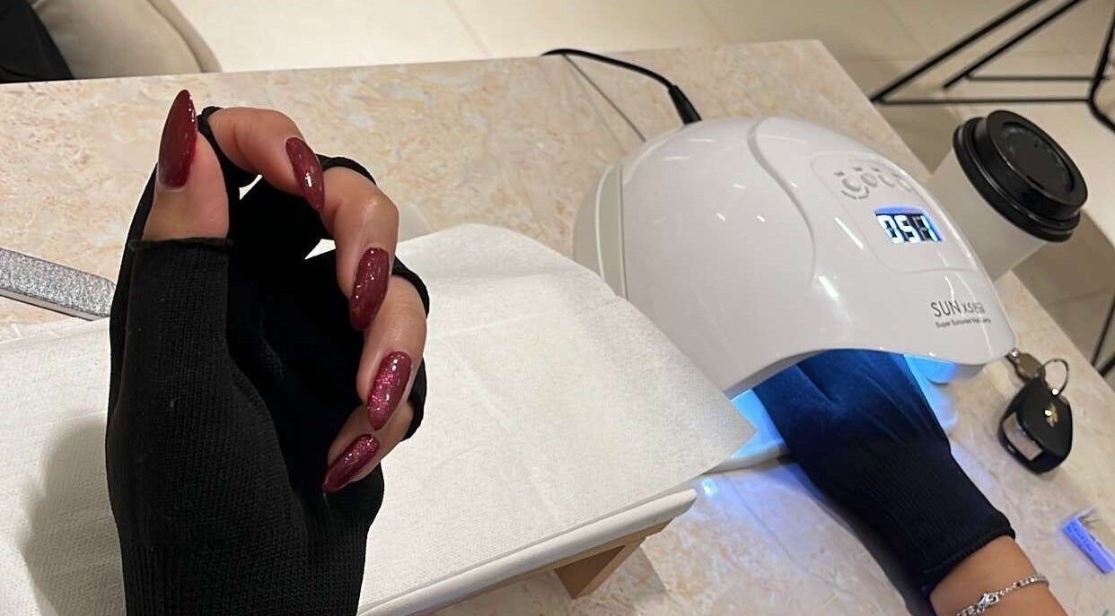 Elegant nail treatment at Nai Spa, Riyadh, Riyadh Province, SA, featuring a UV lamp and red polished nails.