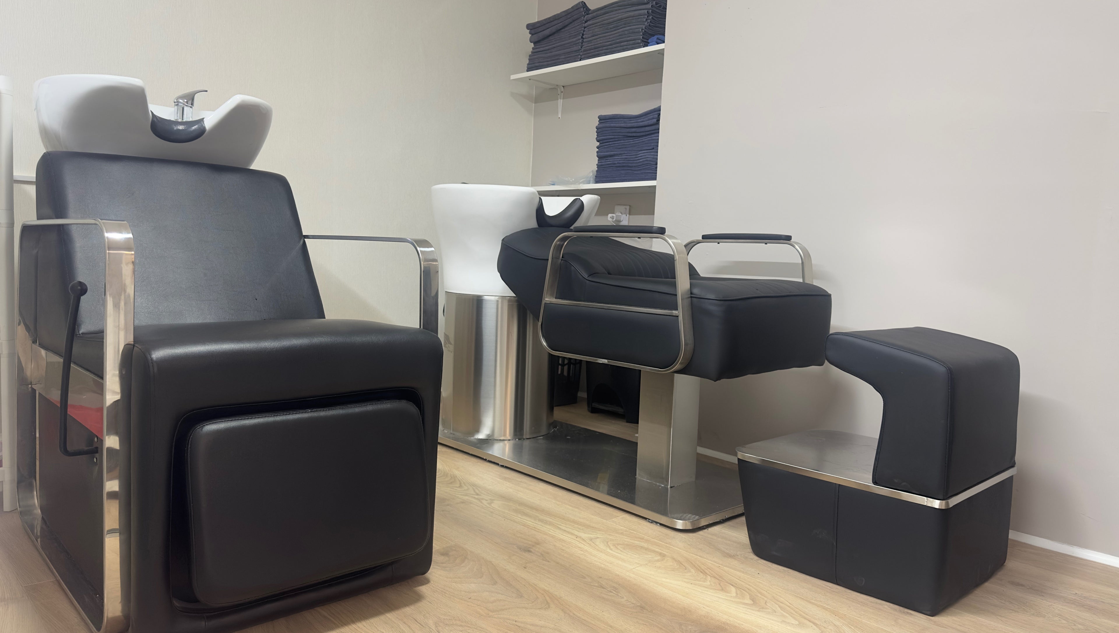 Modern salon wash stations at 真Jin Salon, Warrington, England, GB with sleek black chairs.