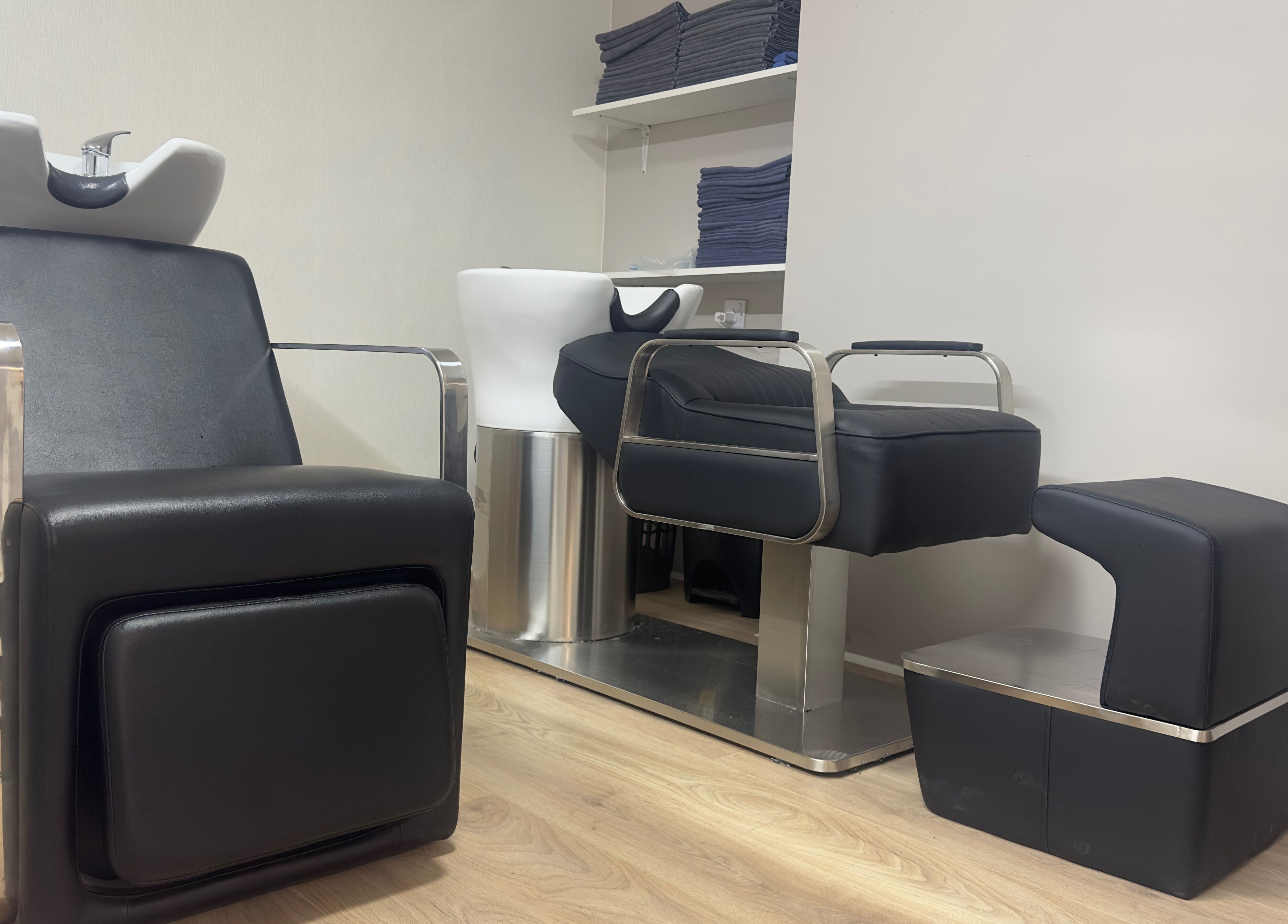 Modern salon wash stations at 真Jin Salon, Warrington, England, GB with sleek black chairs.
