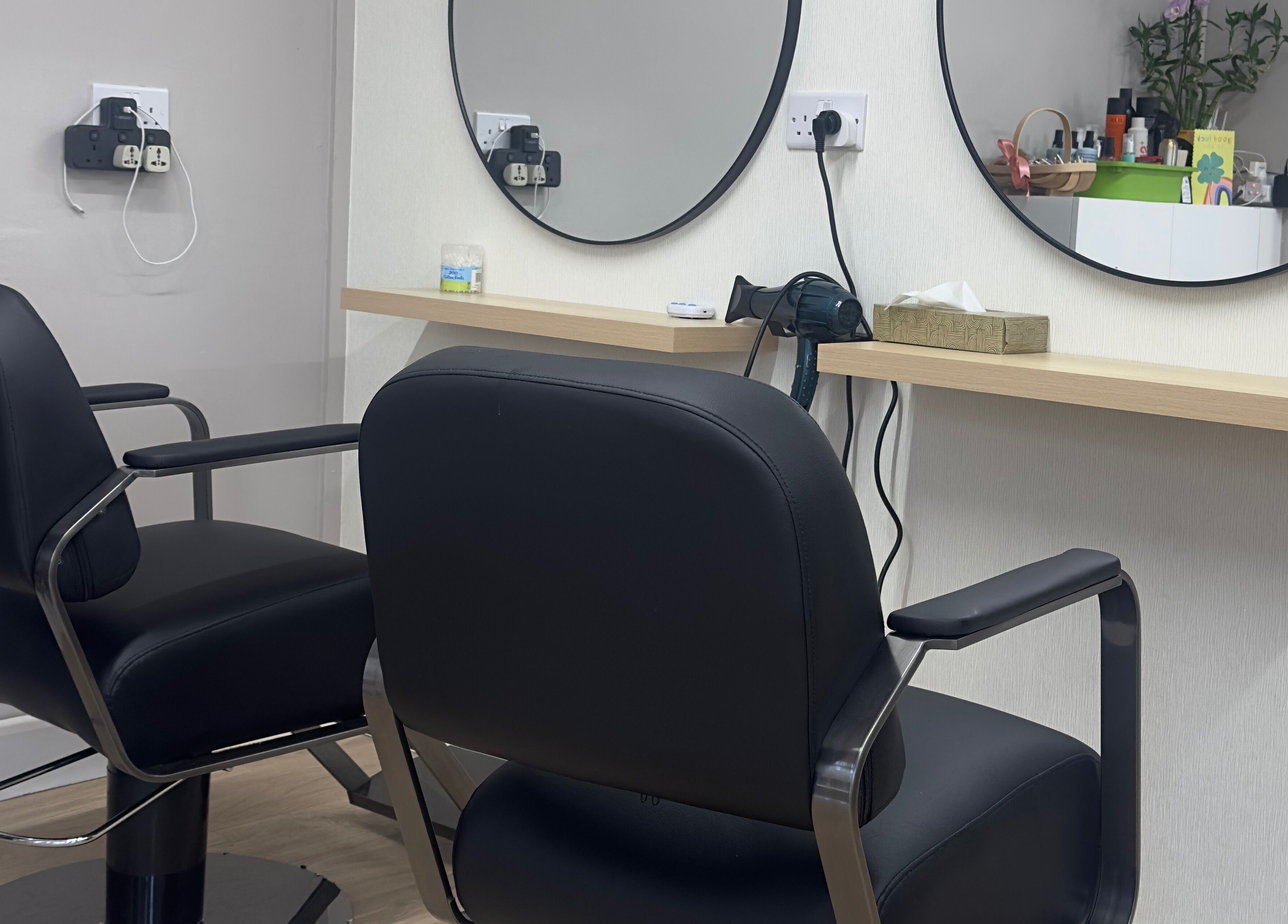 Modern hair styling station at 真Jin Salon, Warrington, England, GB with sleek black chairs and round mirrors.