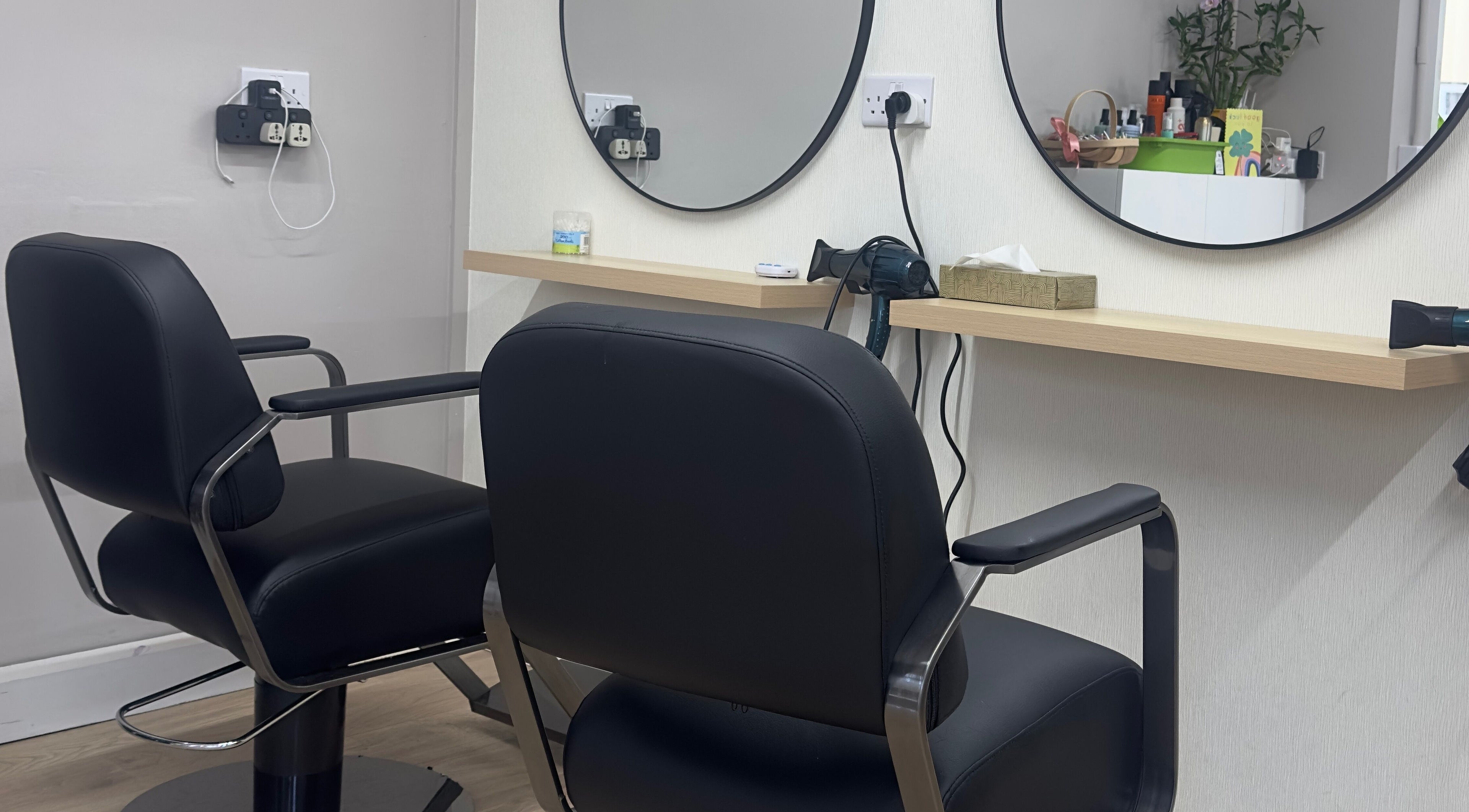 Modern hair styling station at 真Jin Salon, Warrington, England, GB with sleek black chairs and round mirrors.