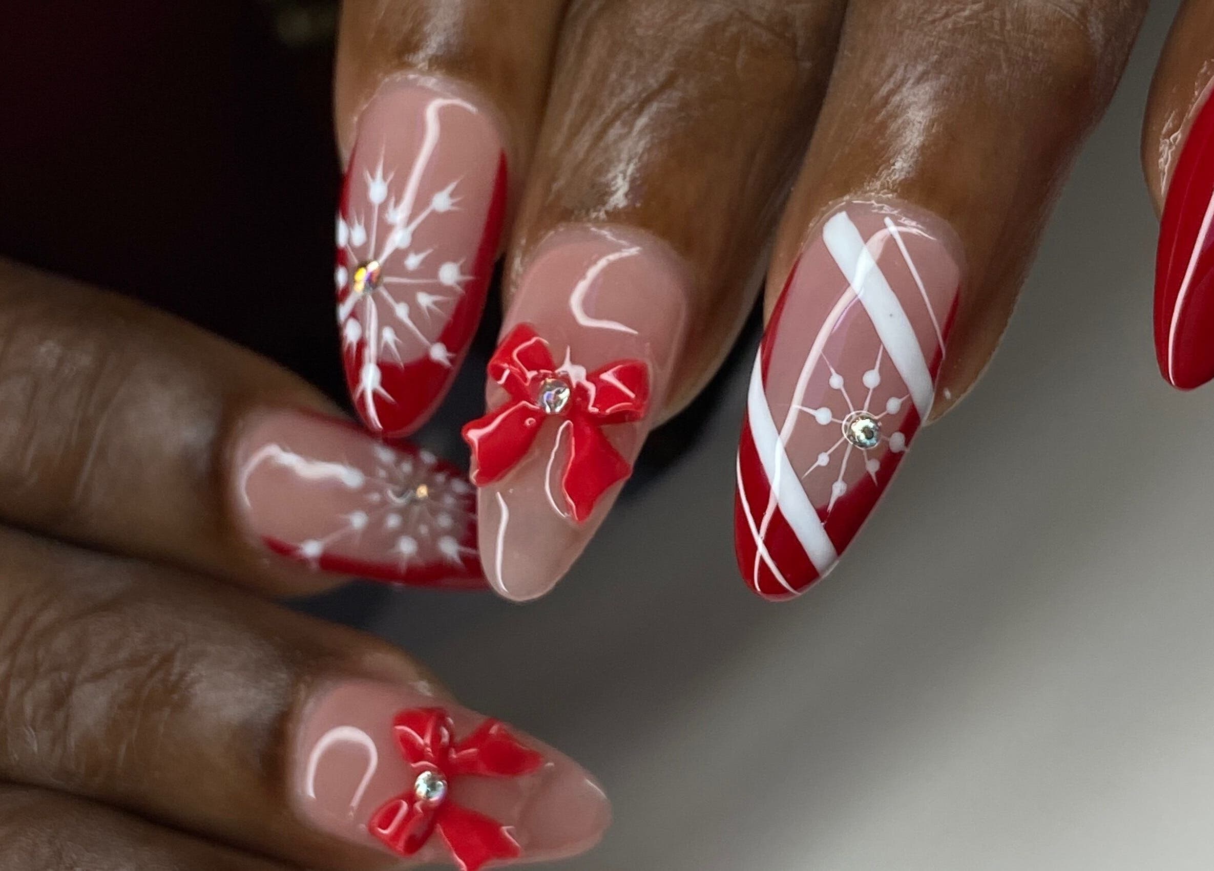 Red and white festive nail art at Kshine Aesthetics, Brievengat, Curaçao, CW. Intricate bows and snowflake designs.
