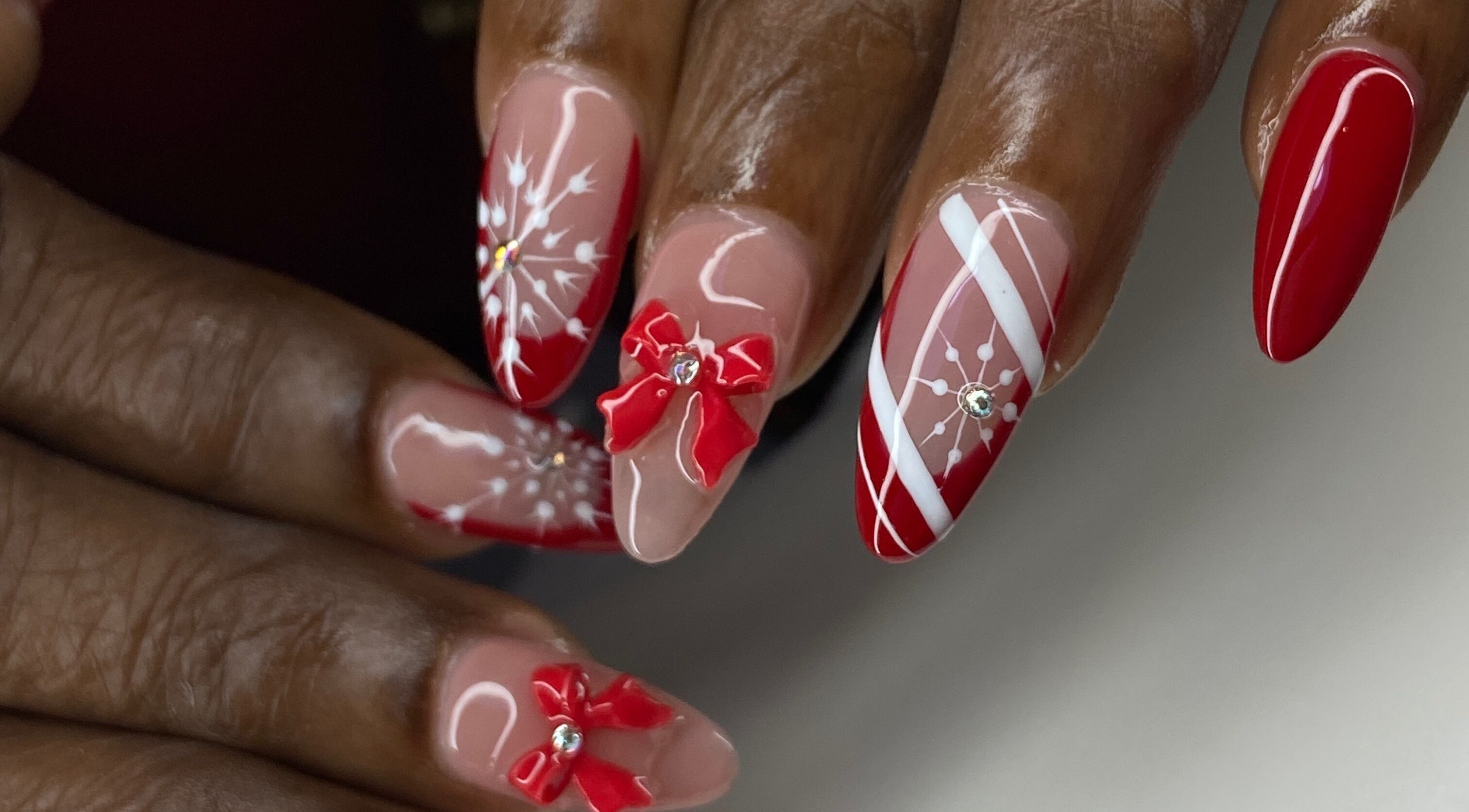 Red and white festive nail art at Kshine Aesthetics, Brievengat, Curaçao, CW. Intricate bows and snowflake designs.