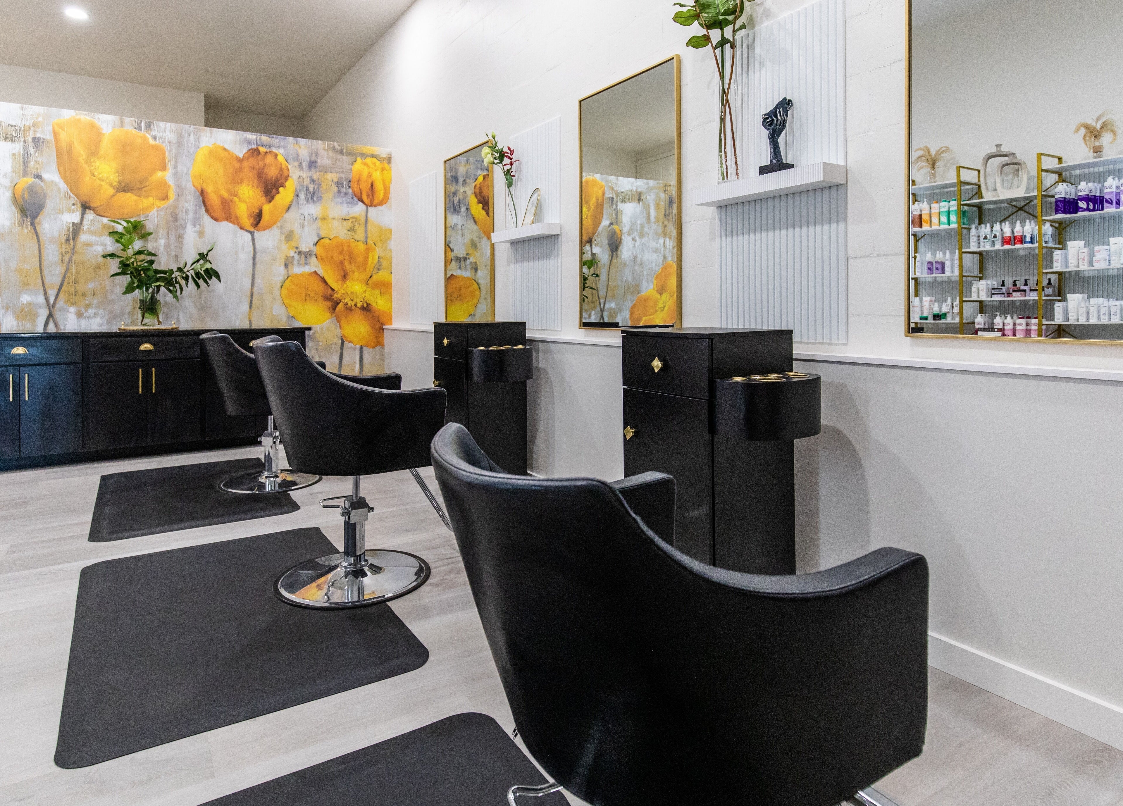 Stylish black chairs at Elysian Salon and Spa, Vero Beach, Florida, US with vibrant yellow floral wall art.