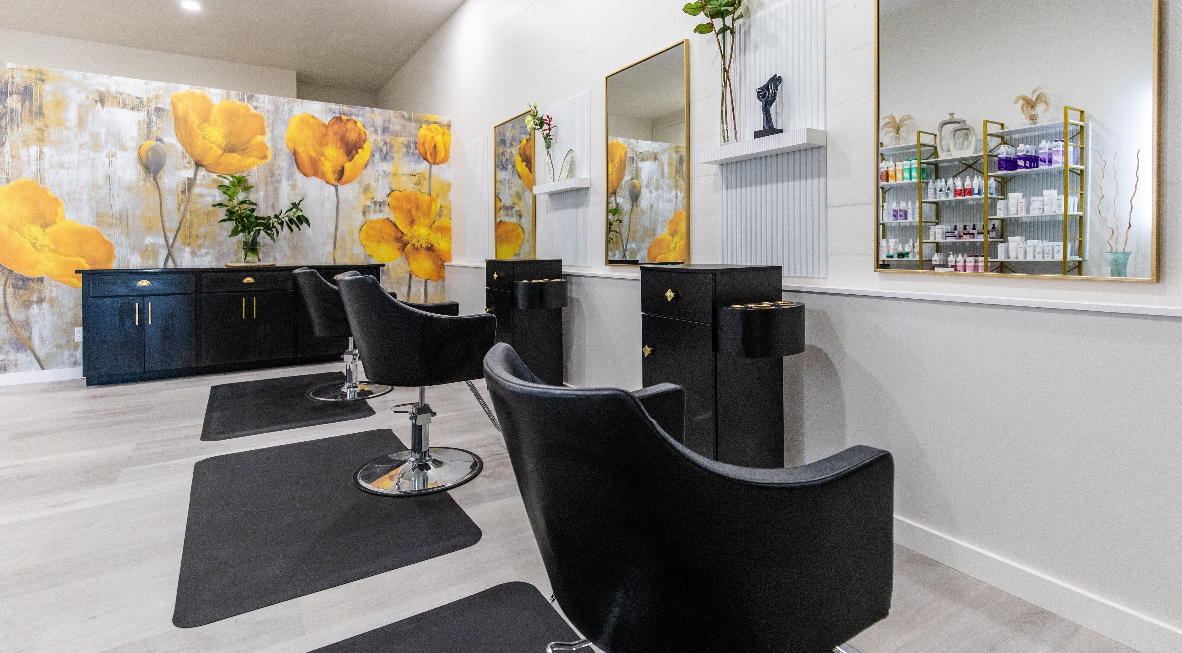Stylish black chairs at Elysian Salon and Spa, Vero Beach, Florida, US with vibrant yellow floral wall art.