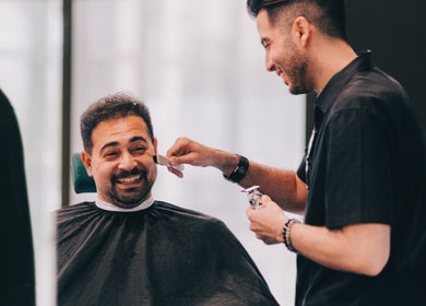 Professional barber shaving a smiling client at BarberBar, Pavilion Embassy, Kuala Lumpur, MY.
