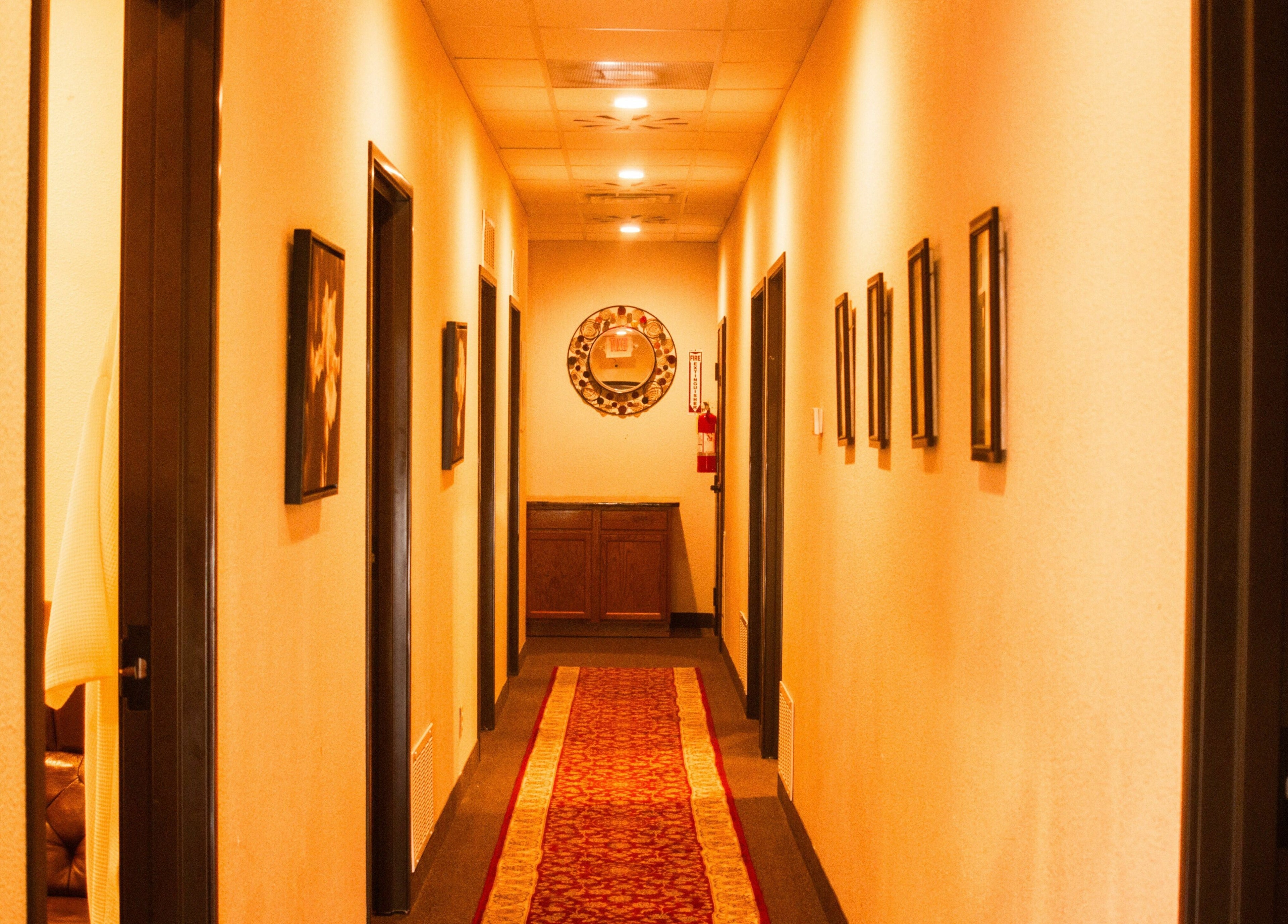 Warm-lit corridor at Bluebonnet Massage, Irving, Texas, US, with art-adorned walls.