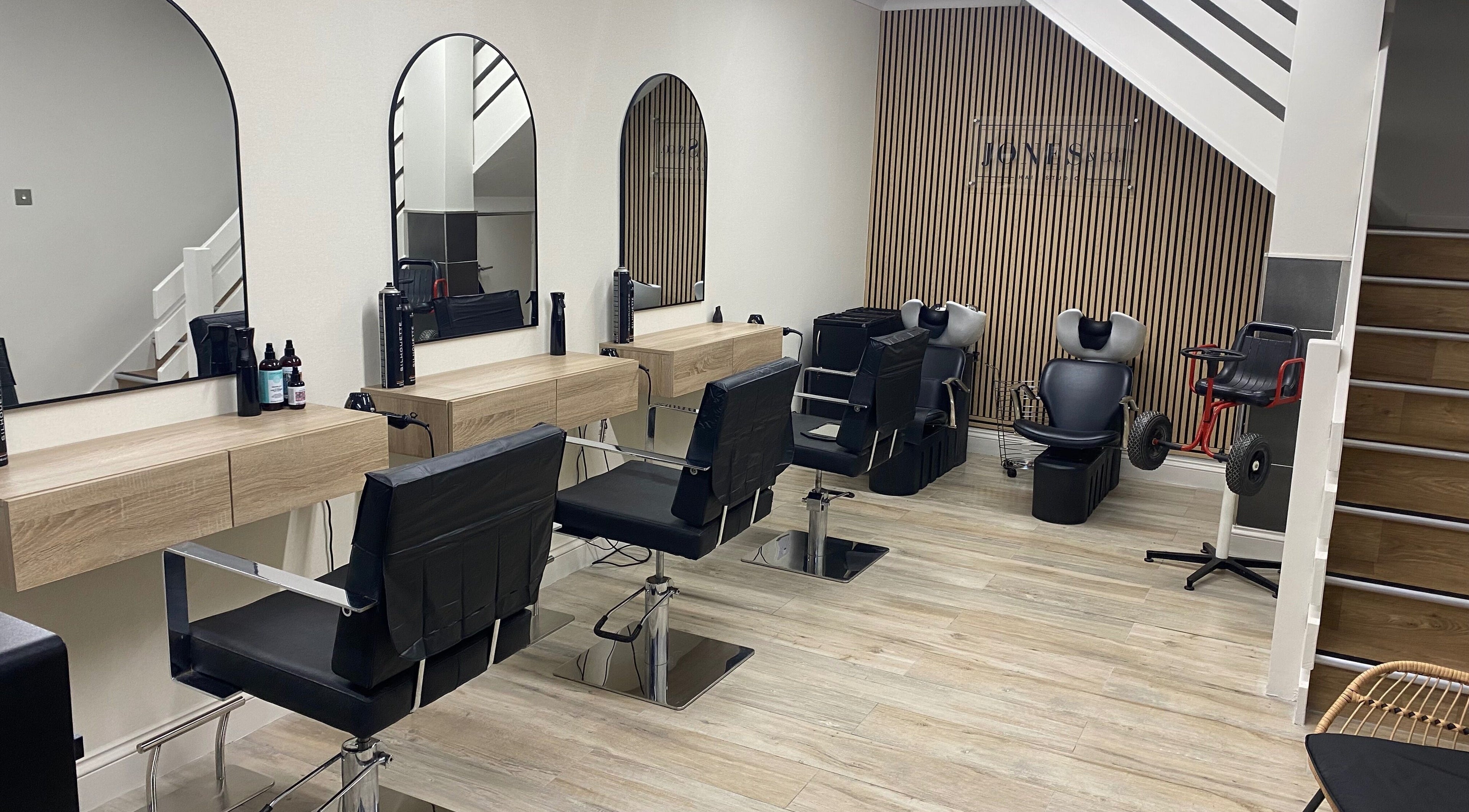 Modern salon interior at Jones & Co, Saint Ives, England, GB, featuring stylish chairs and mirrors.