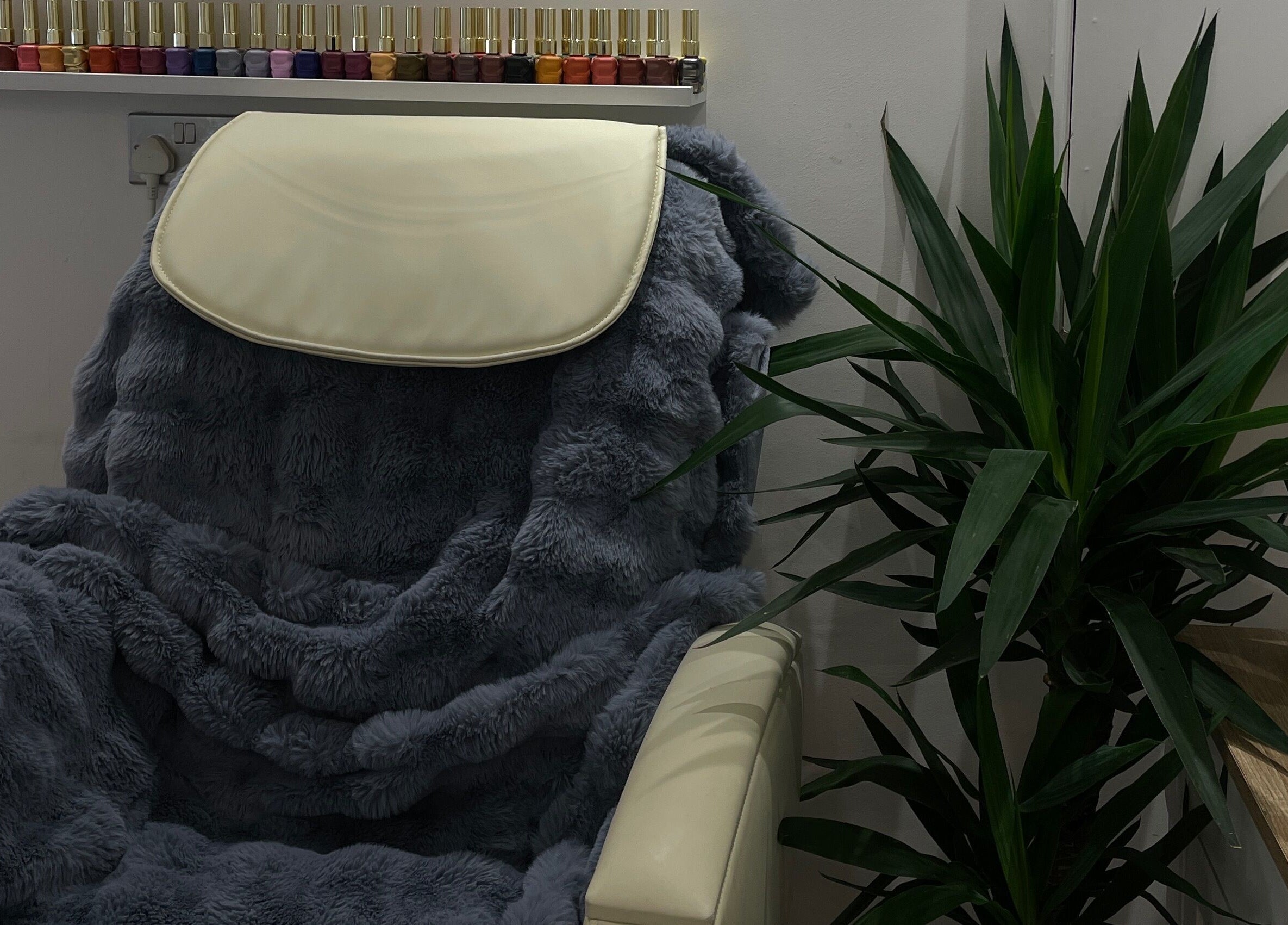 Luxurious chair with plush cover at Bn Studio, Coventry, England, GB, adjacent to vibrant nail polishes.