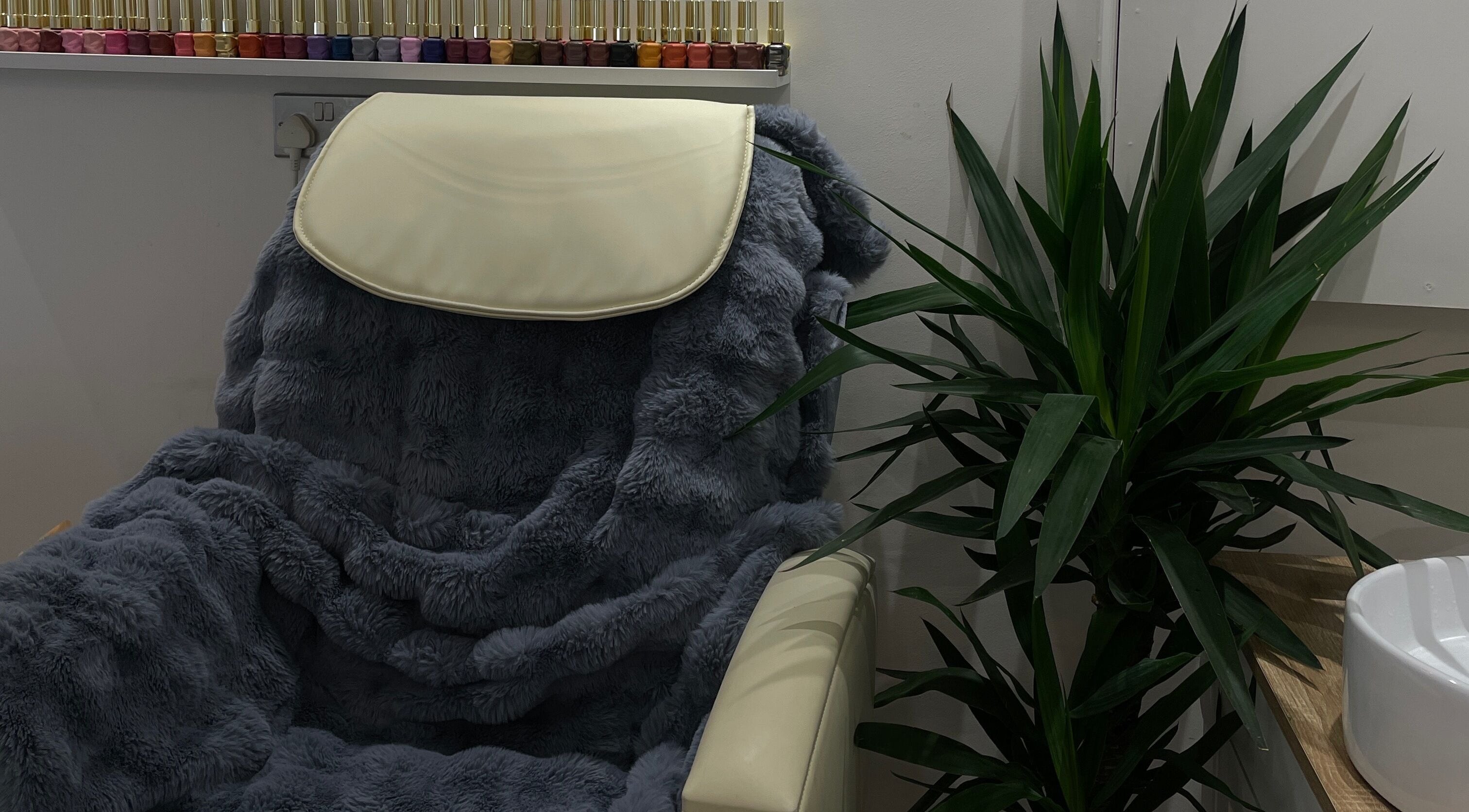 Luxurious chair with plush cover at Bn Studio, Coventry, England, GB, adjacent to vibrant nail polishes.