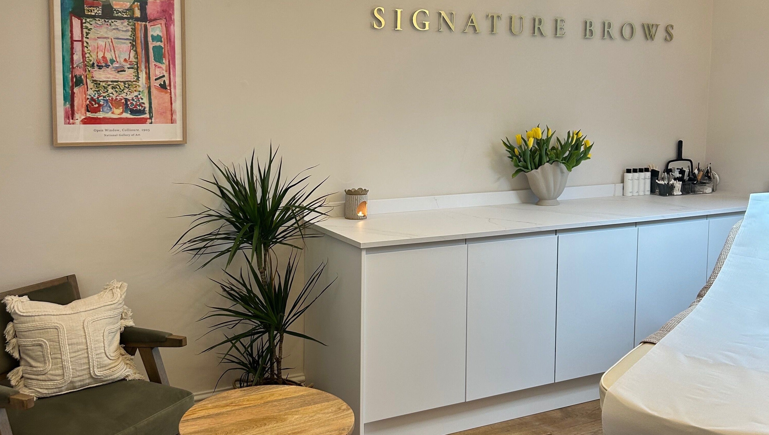 Bright, welcoming interior of Signature Brows in Bridgend, Wales, GB with stylish decor including plants and art.