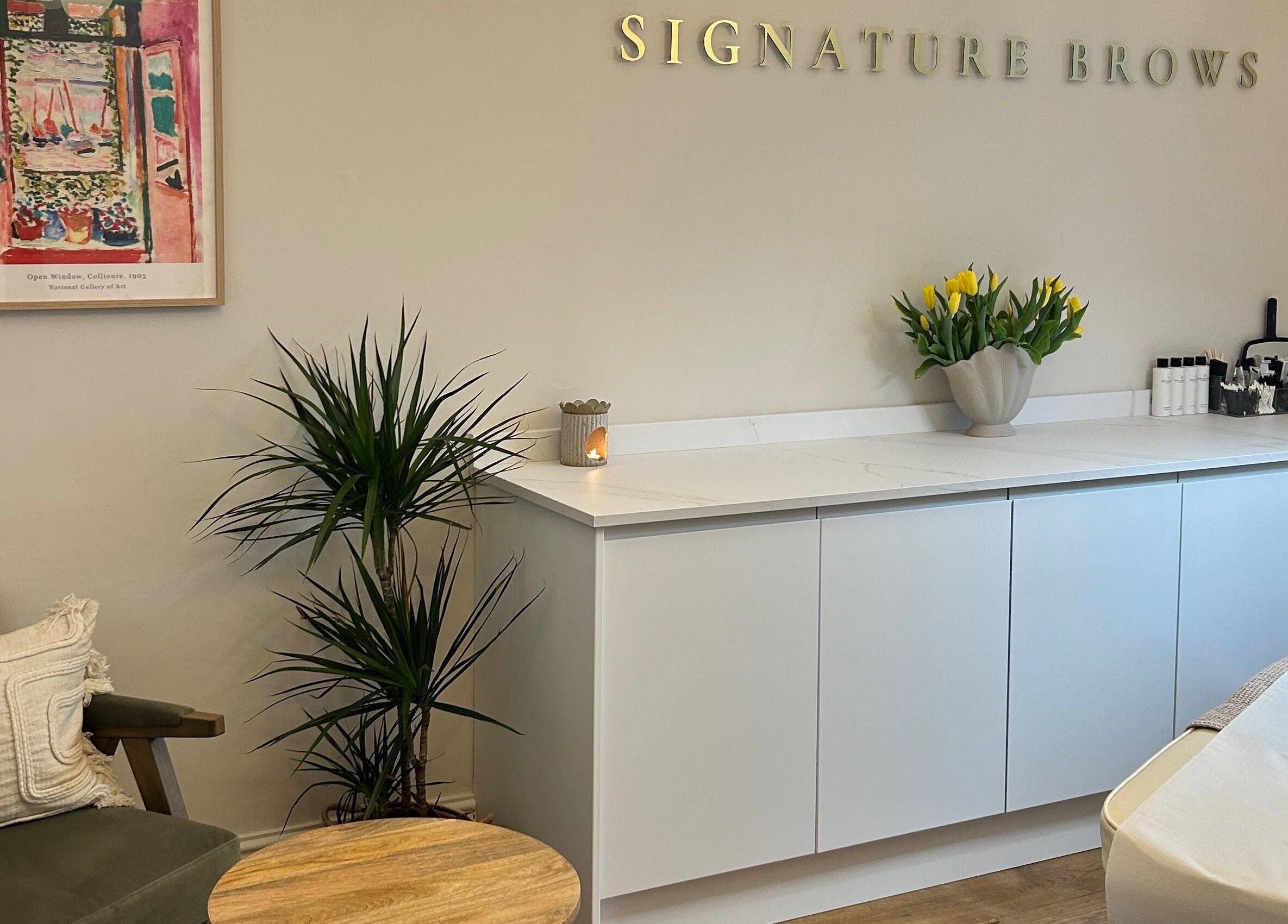 Bright, welcoming interior of Signature Brows in Bridgend, Wales, GB with stylish decor including plants and art.