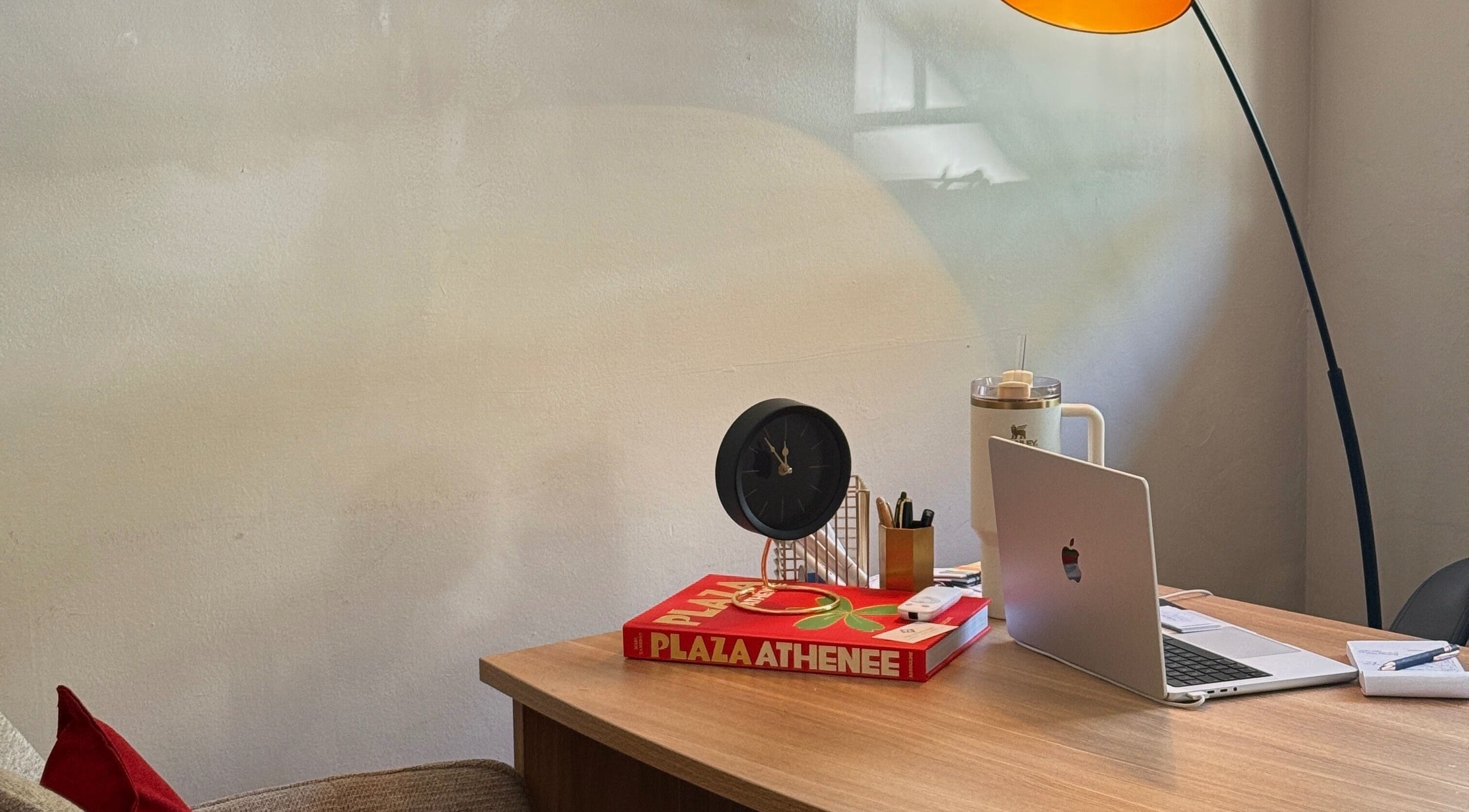 Cozy, elegant desk setup at Mii Health, Johannesburg, Gauteng, ZA, with a lamp, clock, and laptop.