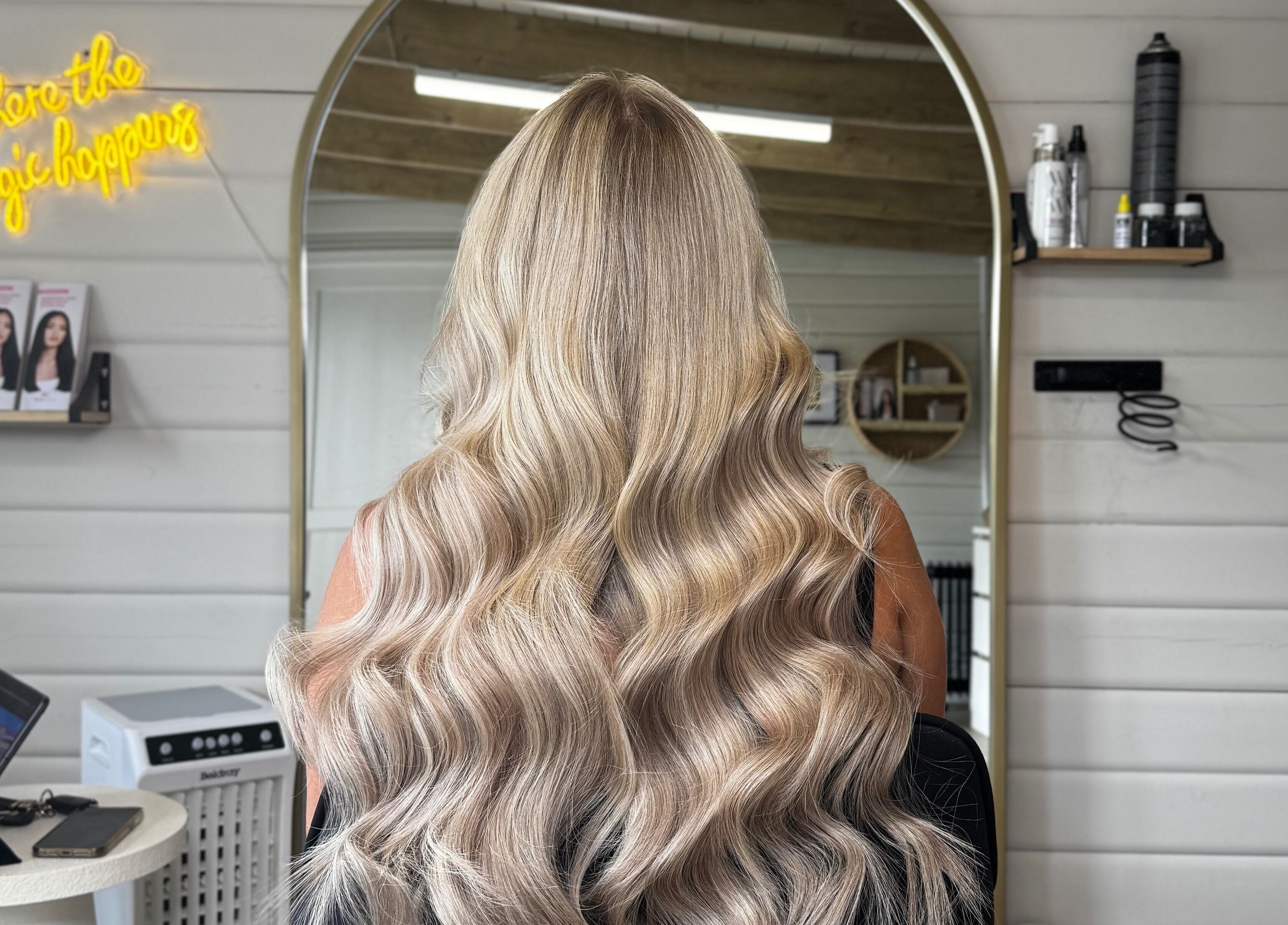 Back view of wavy blonde hair at HD Hairextensions, Runwell, England, GB showcasing salon interior.