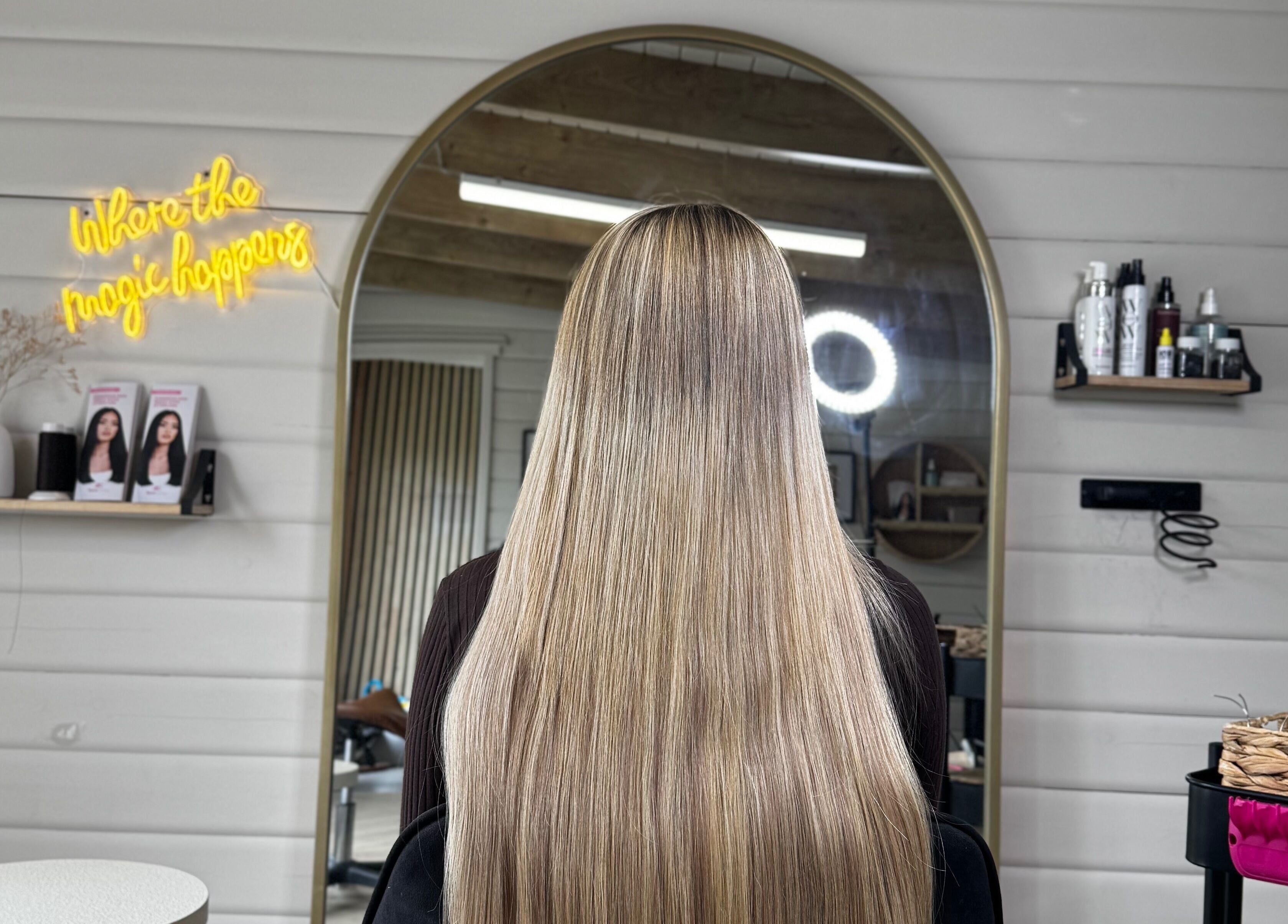 Elegant hairstyle in mirror at HD Hairextensions, Runwell, England, GB. Modern salon interior with products displayed.