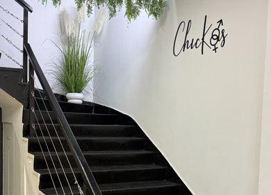 Escalera negra decorativa en Chickasalon, Santiago, Región Metropolitana, CL con plantas y logo en la pared.