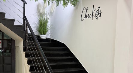 Escalera negra decorativa en Chickasalon, Santiago, Región Metropolitana, CL con plantas y logo en la pared.