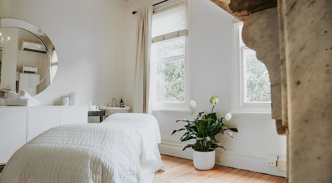 Tranquil spa room at A Rose Organic Beauty, Berry, New South Wales, AU featuring white decor and lush greenery.