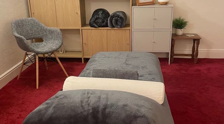 Serene massage room at Leamington Therapy, Royal Leamington Spa, England, GB featuring a comfy chair and massage bed.