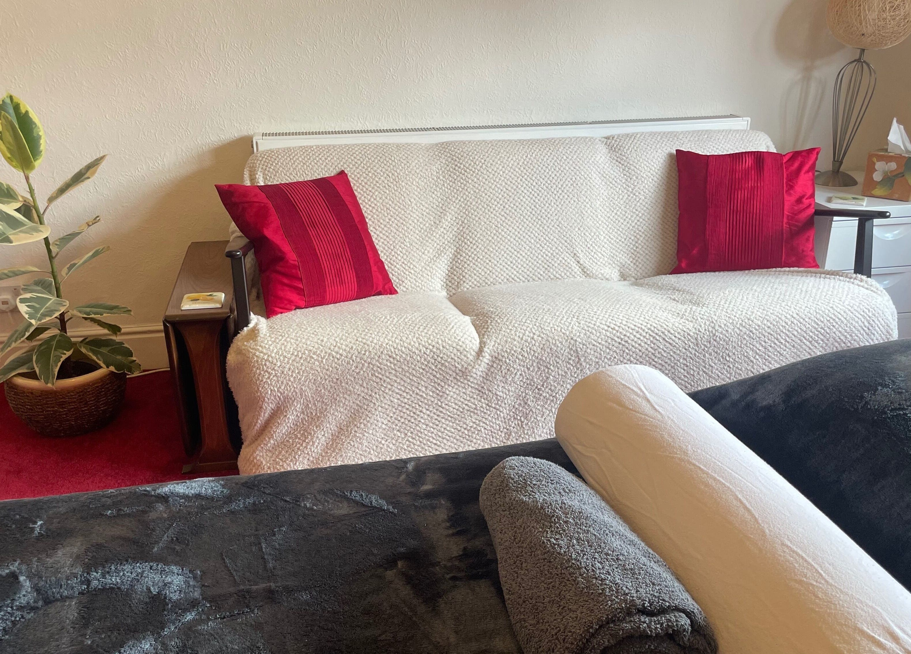 Comfortable therapy room at Leamington Therapy, Royal Leamington Spa, England, with plush sofa and decor.