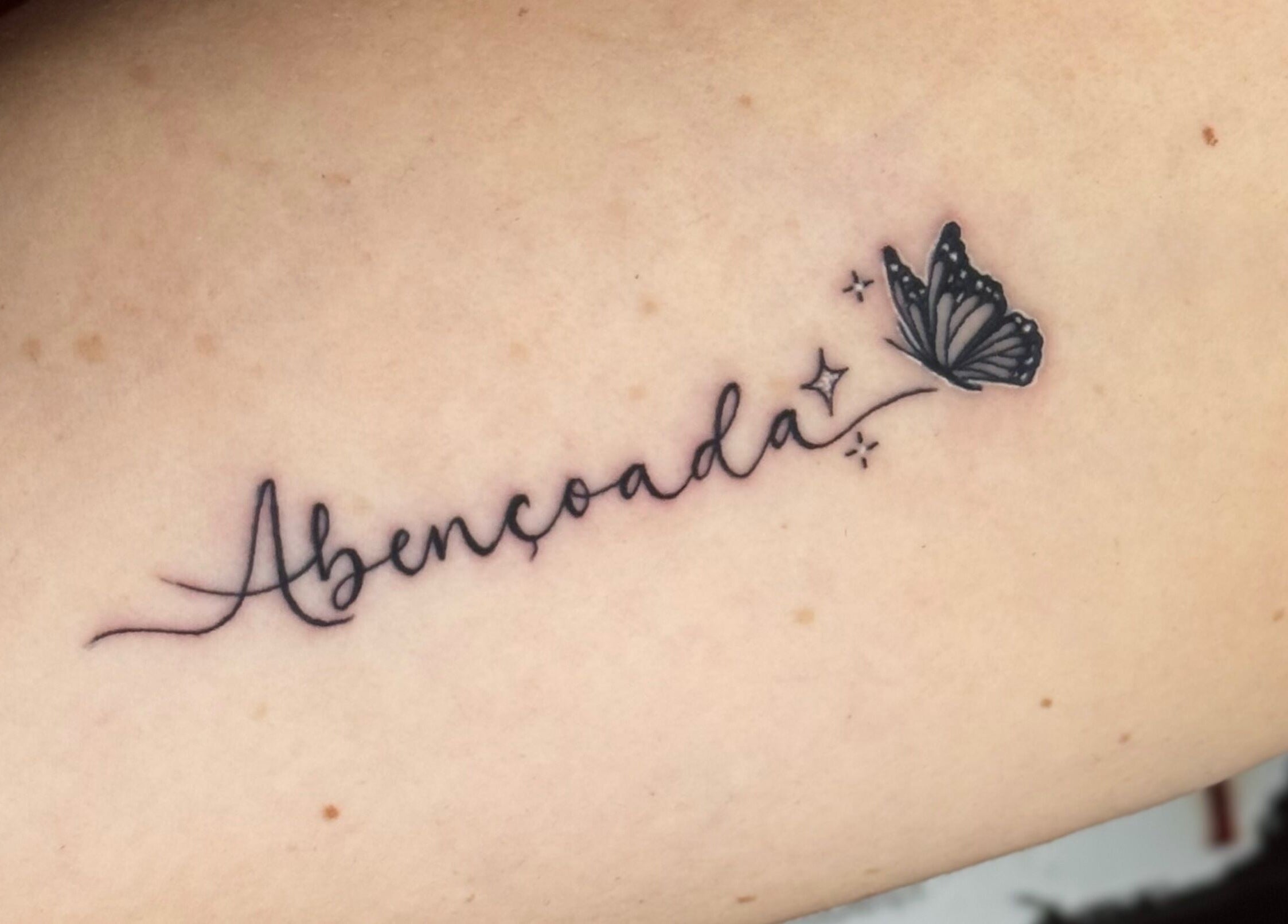 Tatuagem delicada 'Abençoada' com borboleta no Renan Campion Tattoo, São Paulo, São Paulo, BR.