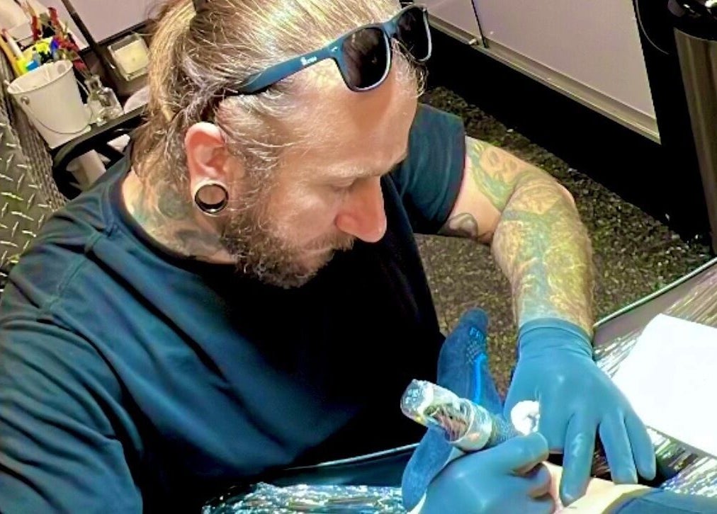 Artista tatuador em Renan Campion Tattoo, São Paulo, criando uma tatuagem detalhada em cliente.