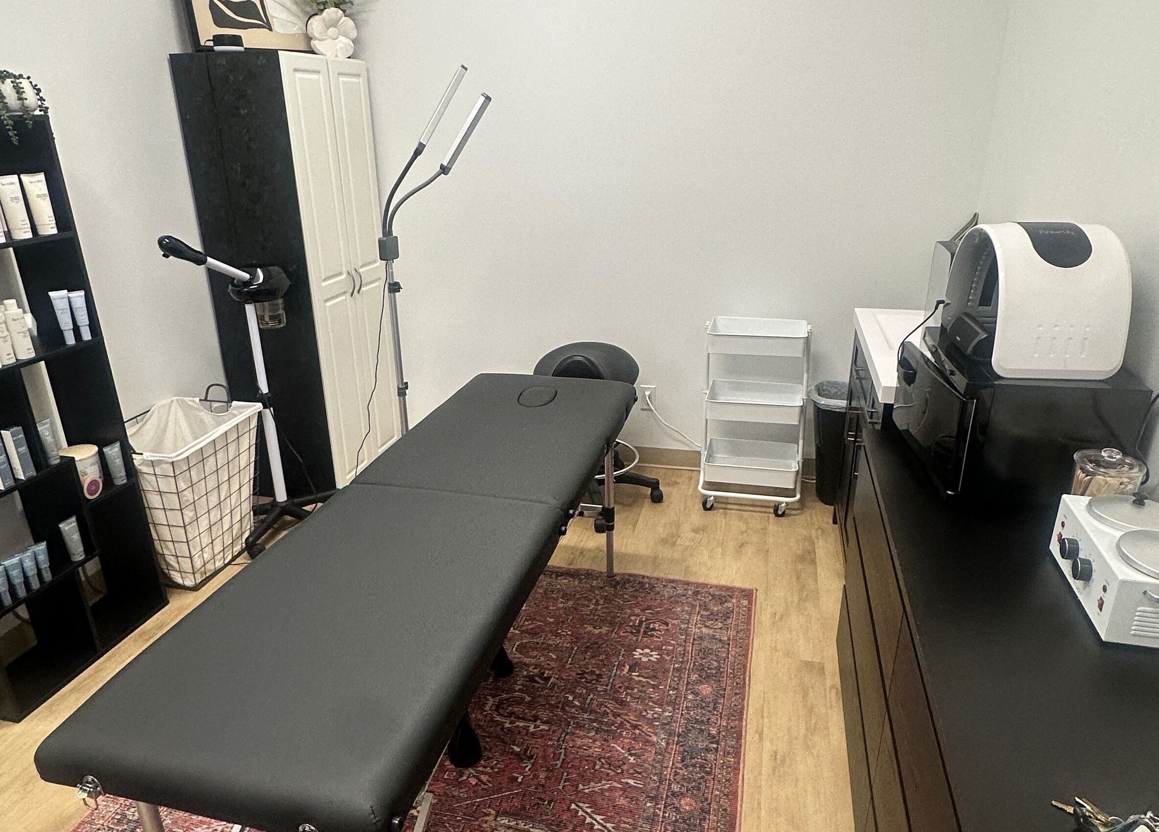 Cozy treatment room at Em's Esthetics in Pleasant Grove, Utah, US, featuring a black massage table and skincare products.