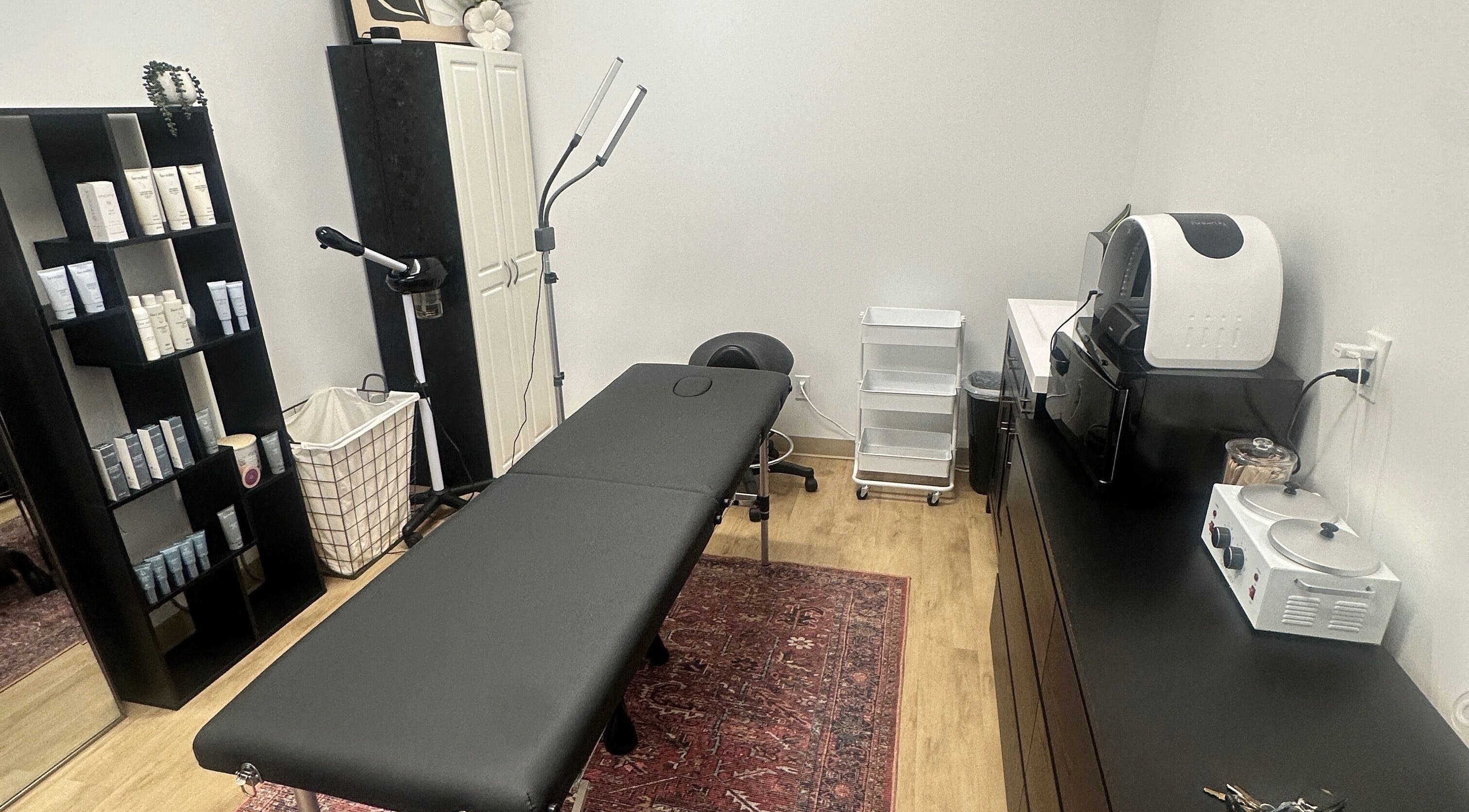 Cozy treatment room at Em's Esthetics in Pleasant Grove, Utah, US, featuring a black massage table and skincare products.