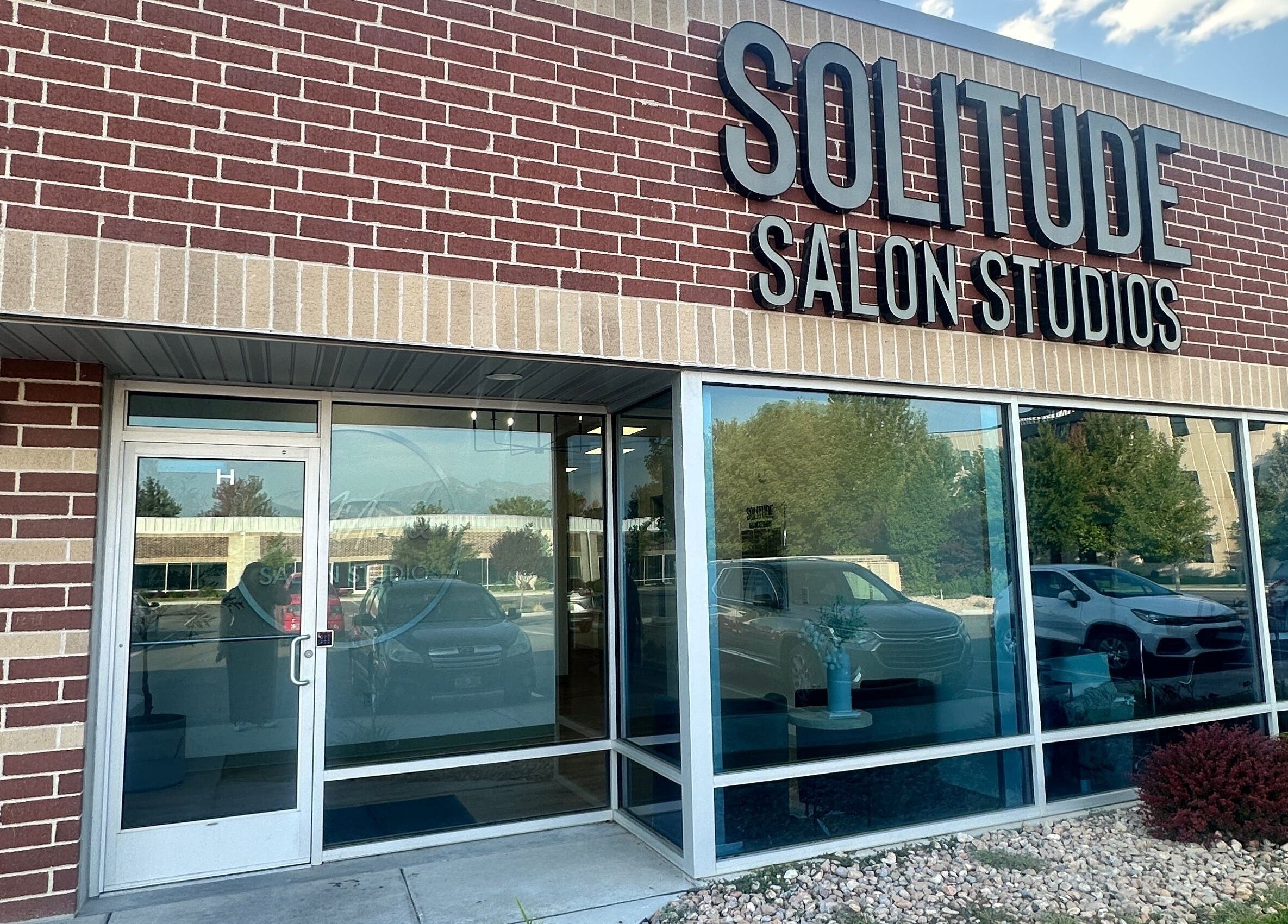 Front entrance of Em's Esthetics in Pleasant Grove, Utah, US featuring modern glass doors and signage.