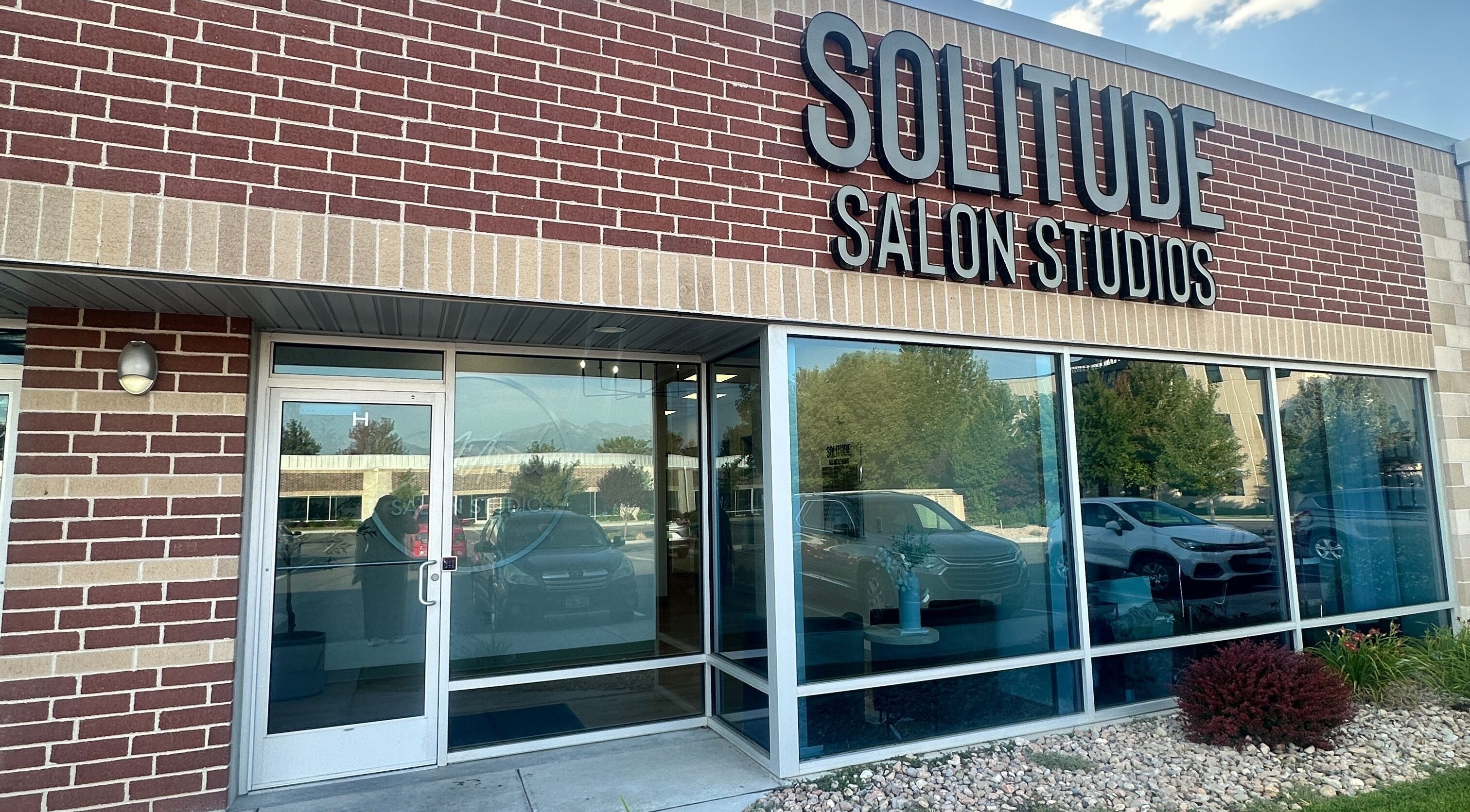 Front entrance of Em's Esthetics in Pleasant Grove, Utah, US featuring modern glass doors and signage.