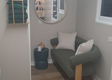 Inviting lounge area at The Hair Cabin in Featherstone, England with a green sofa and minimalist decor.