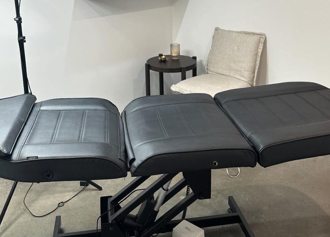 Treatment room at Feather and Arch Cosmetic Tattoo, Mooloolaba, Queensland, AU with an adjustable black chair.