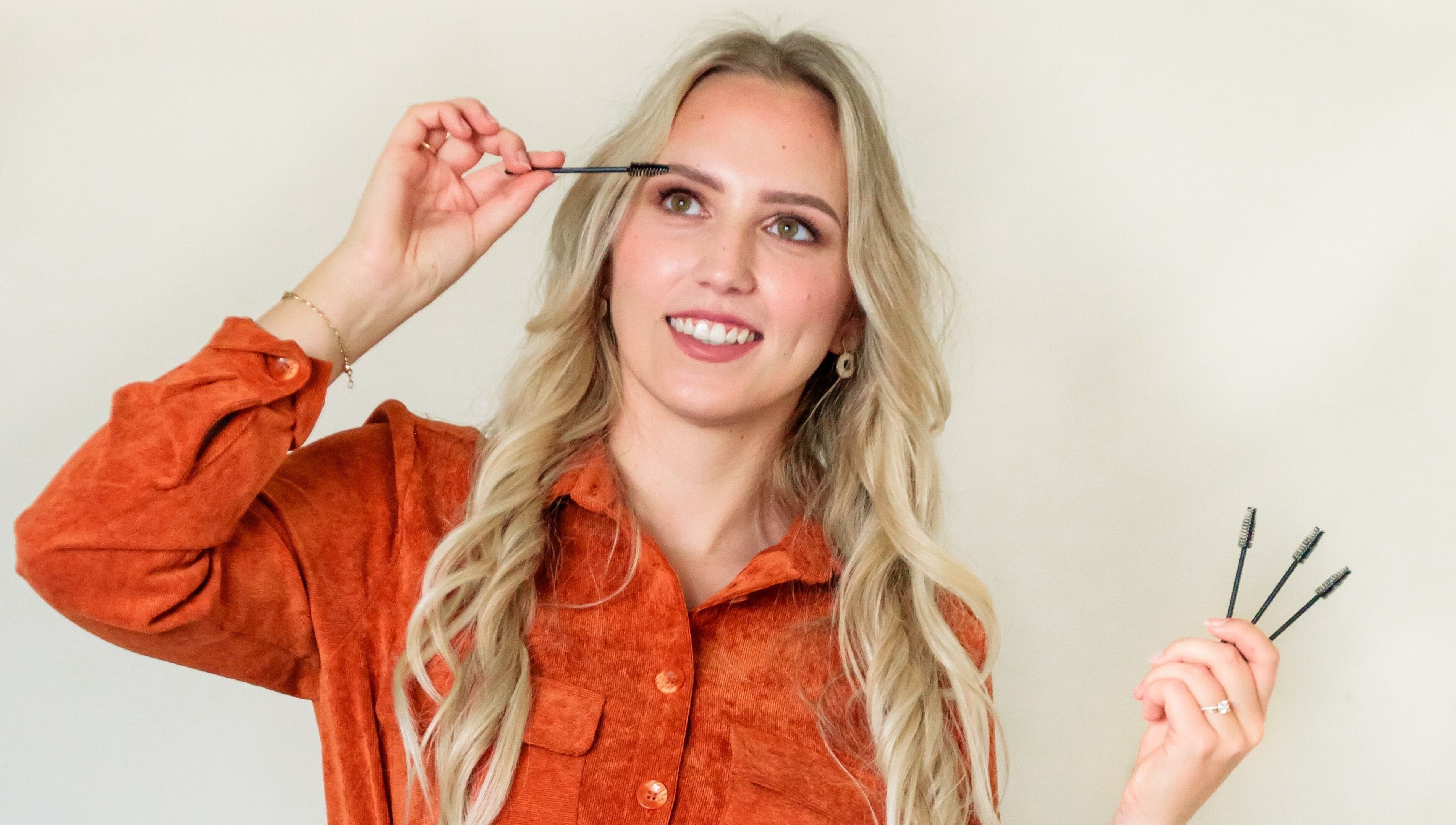 Vrouw in oranje blouse bij CLS Care, Lochristi, Vlaams Gewest, BE, past make-up borstel toe.