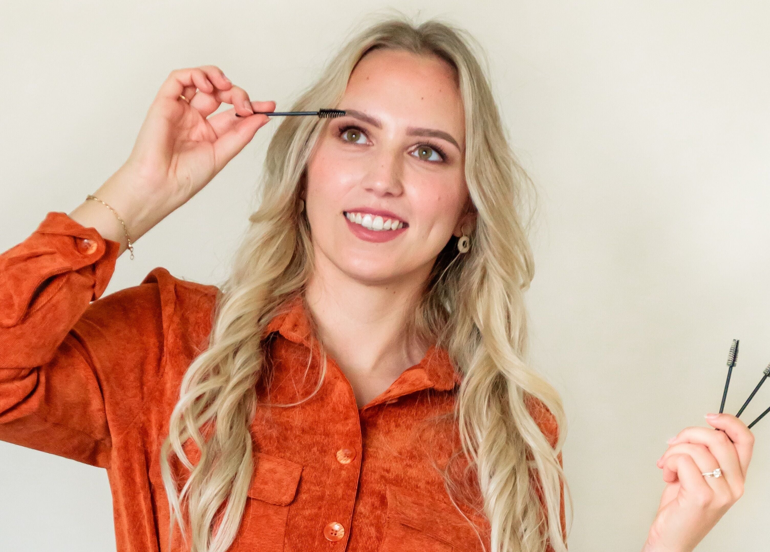 Vrouw in oranje blouse bij CLS Care, Lochristi, Vlaams Gewest, BE, past make-up borstel toe.