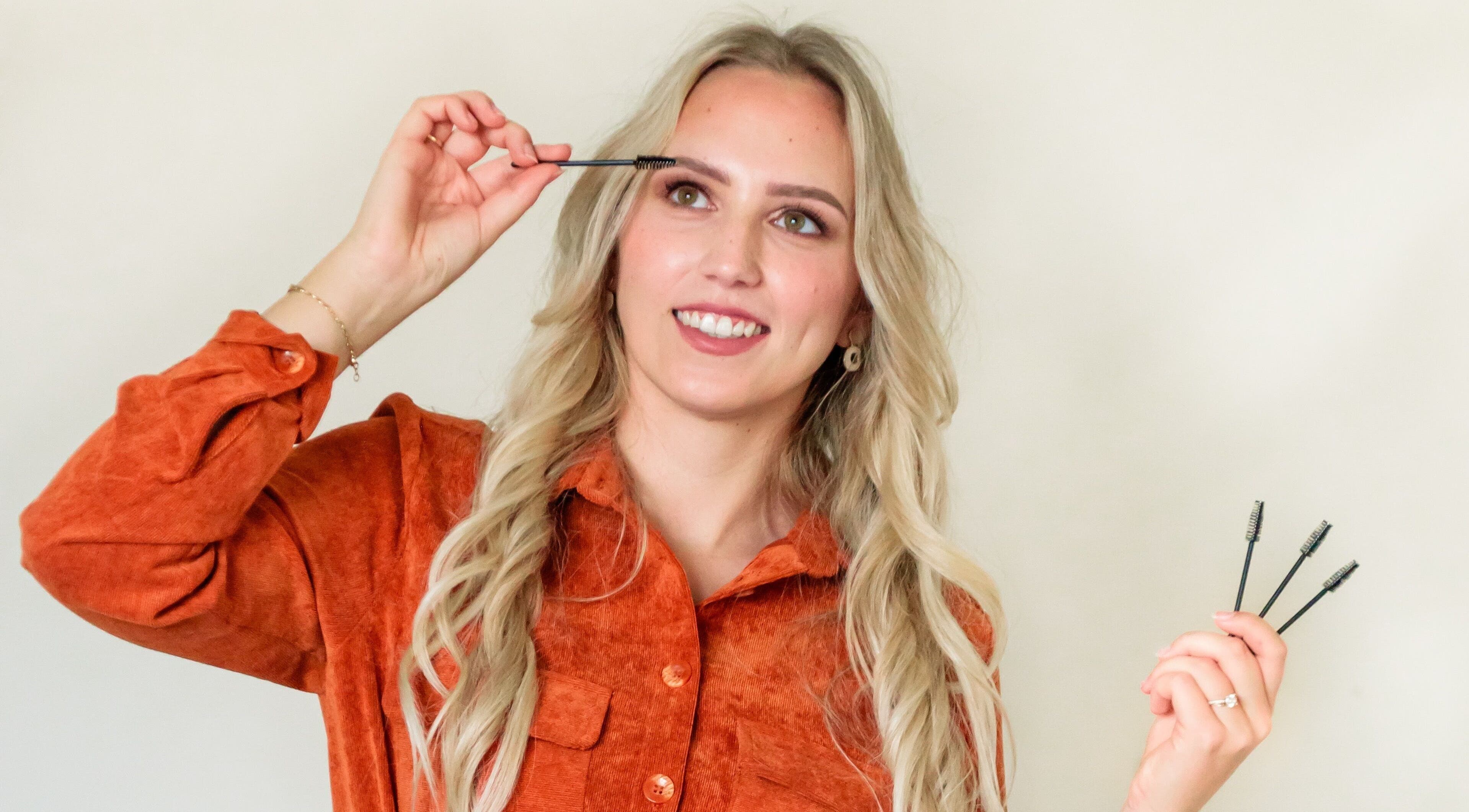 Vrouw in oranje blouse bij CLS Care, Lochristi, Vlaams Gewest, BE, past make-up borstel toe.