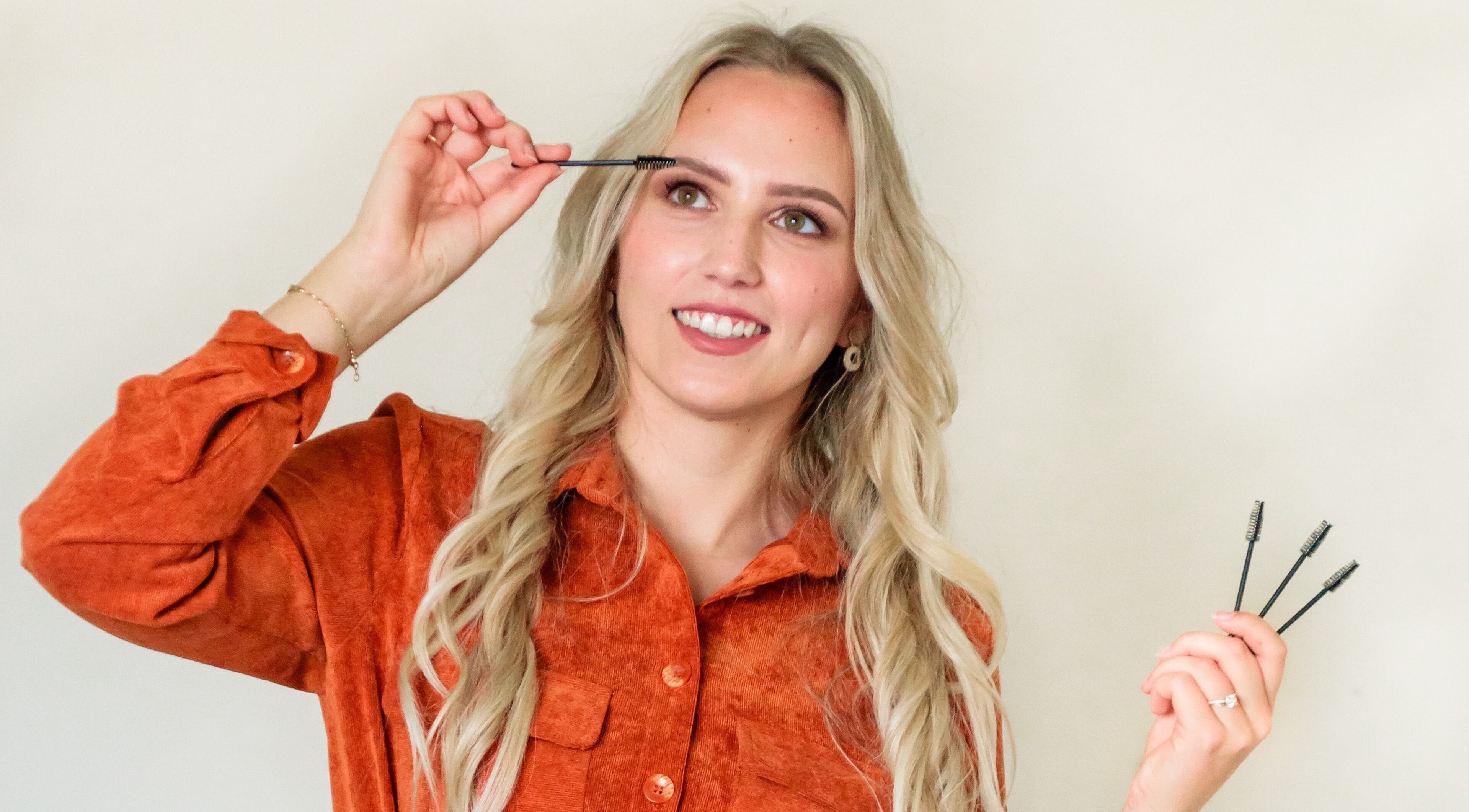 Vrouw in oranje blouse bij CLS Care, Lochristi, Vlaams Gewest, BE, past make-up borstel toe.