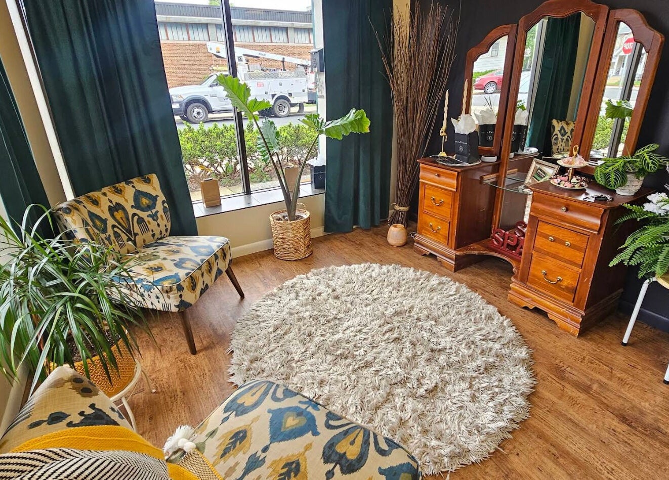 Elegant seating area at Prohibited Face and Body Bar, Quakertown, Pennsylvania, US. Warm decor with mirror and plants.