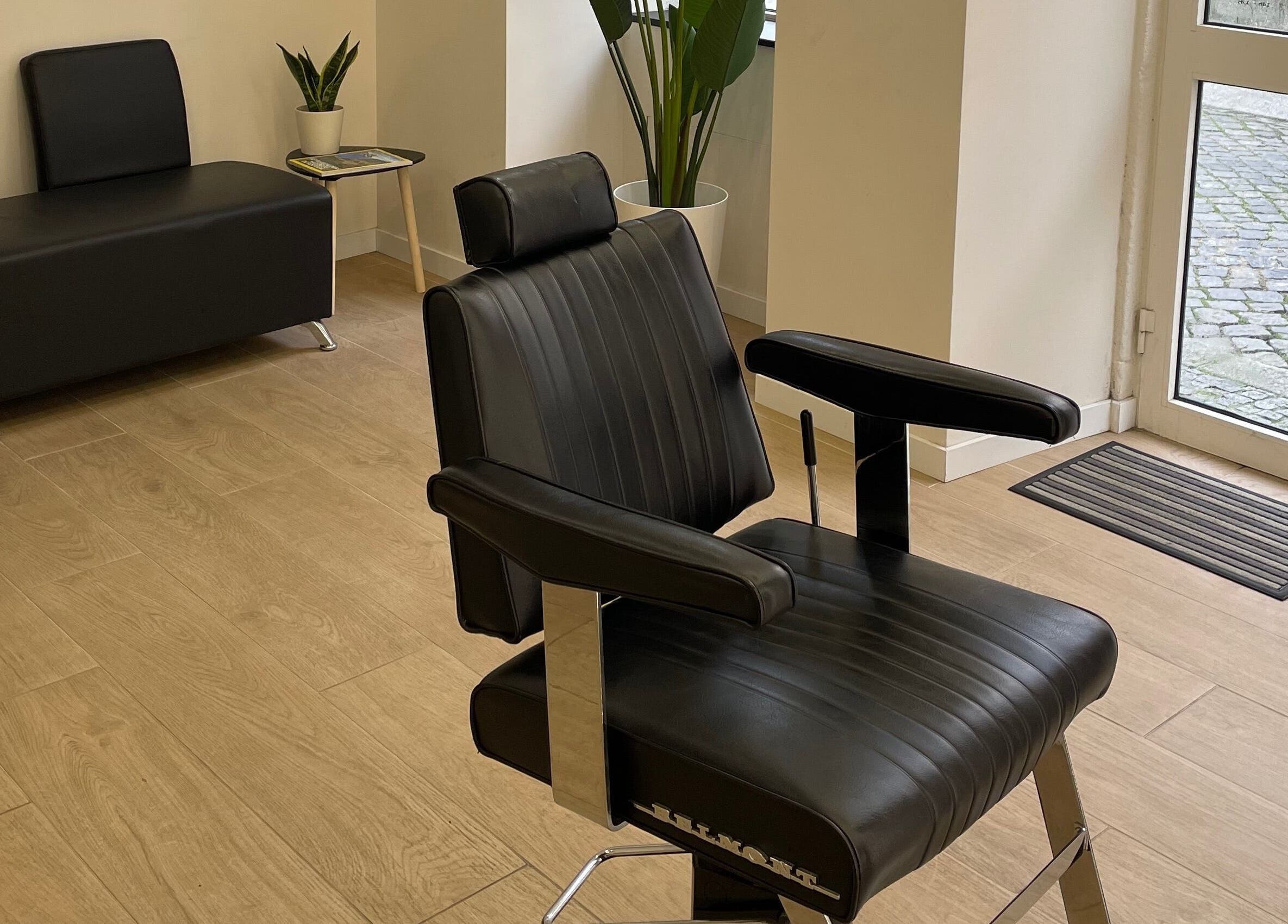 Cadeira de barbeiro elegante em Templum Barbearia, Esposende, Braga, PT, com piso de madeira e decoração moderna.