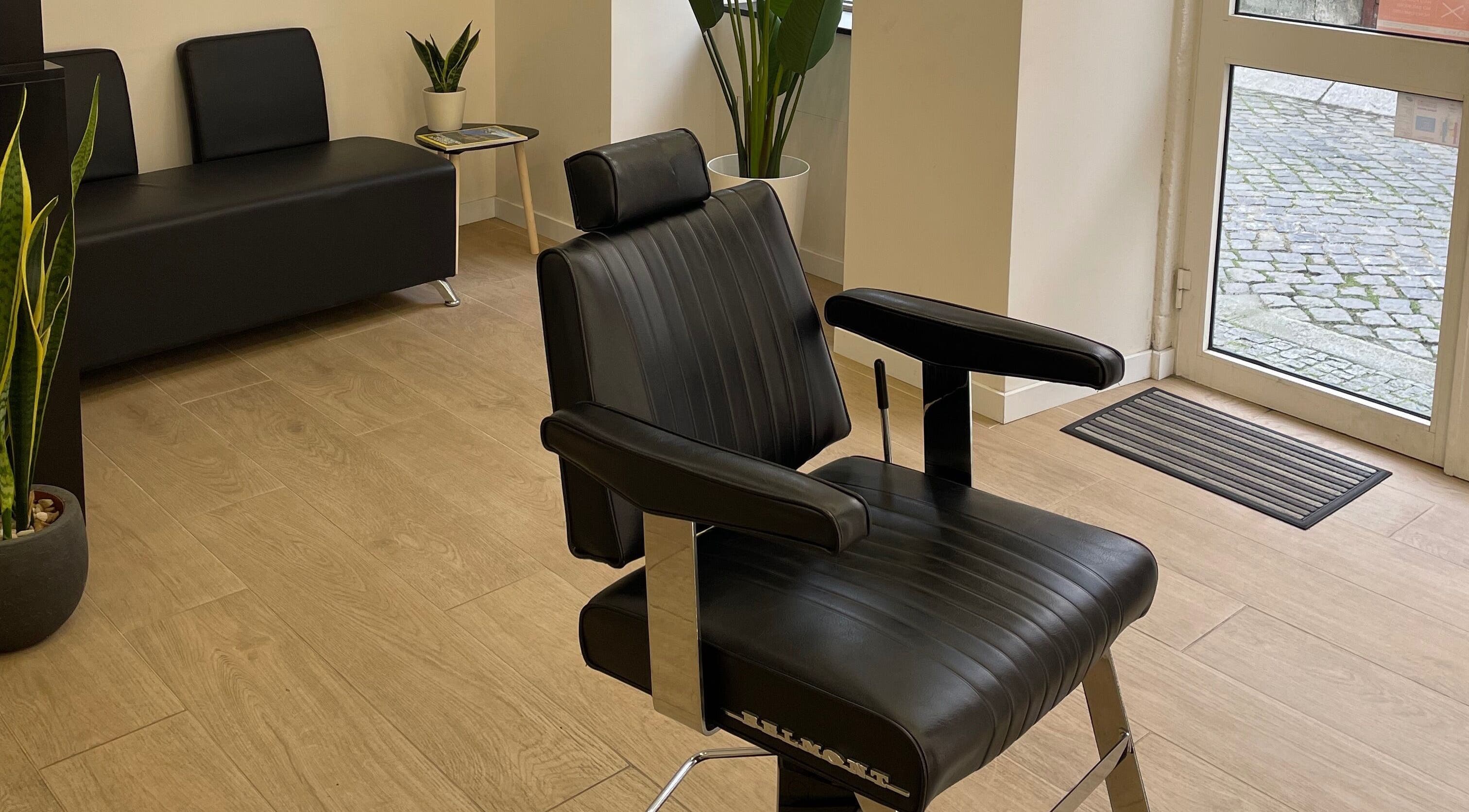 Cadeira de barbeiro elegante em Templum Barbearia, Esposende, Braga, PT, com piso de madeira e decoração moderna.