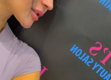 Close-up of woman next to Hivi's Hair & Beauty Salon sign in Hamilton, Ontario, CA.