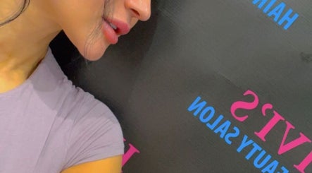 Close-up of woman next to Hivi's Hair & Beauty Salon sign in Hamilton, Ontario, CA.