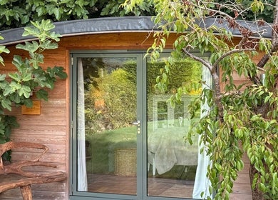 Charming wooden cabin of Fig Tree Cabin in Box, England, GB with lush greenery and cozy decor.