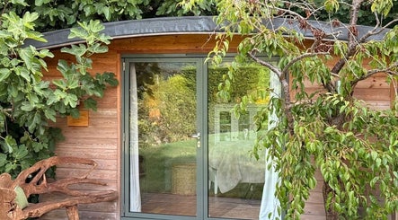 Charming wooden cabin of Fig Tree Cabin in Box, England, GB with lush greenery and cozy decor.